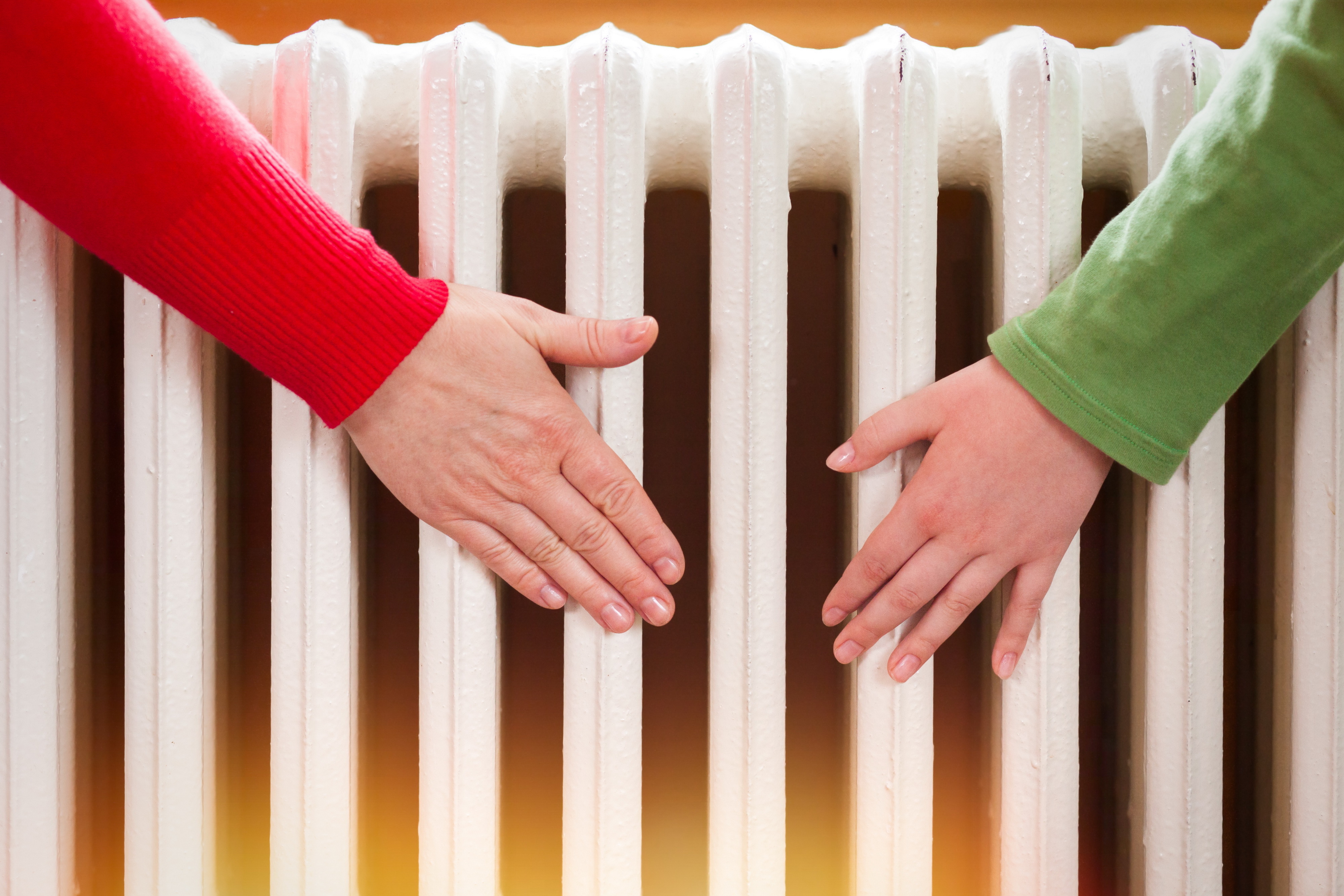 Two,Hands,Touching,The,Radiator,To,Check,Whether,Heated