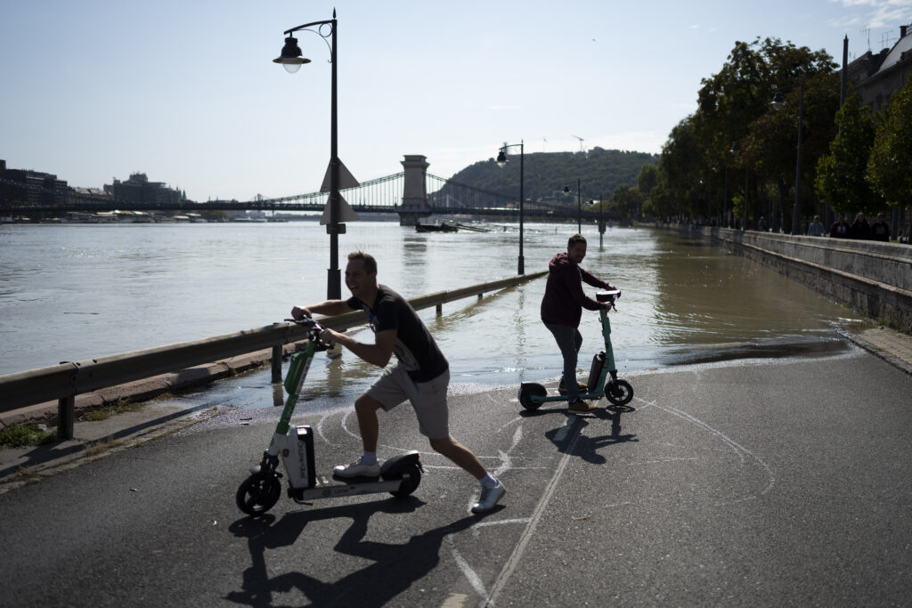 People ride scooters next to the flooded Danube river in central Budapest Friday, Sept. 20, 2024. (AP Photo/Denes Erdos)