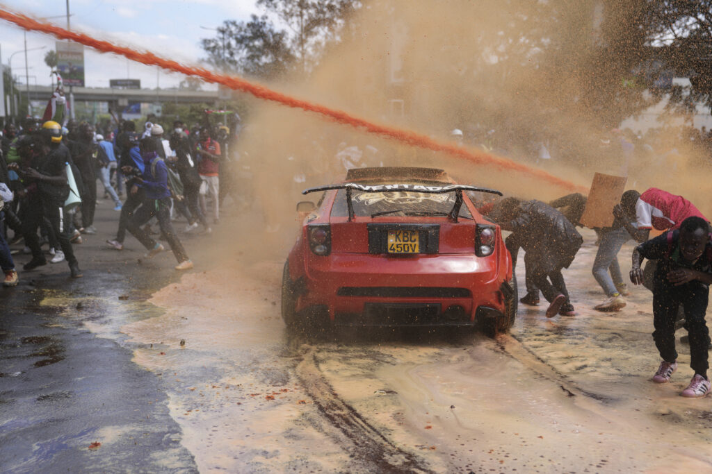 Protesters scatter as Kenya police spray water cannon at them during a protest over proposed tax hikes in a finance bill in downtown Nairobi, Kenya Tuesday, June 25, 2024. (AP Photo/Brian Inganga)