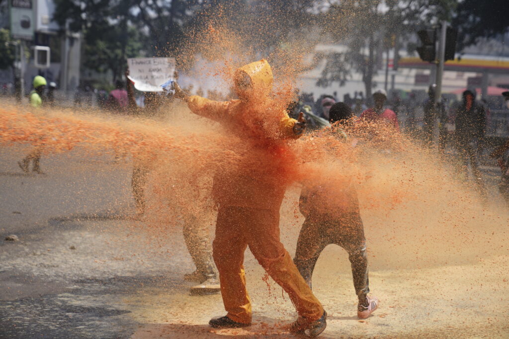 Protesters scatter as Kenya police spray water canon at them during a protest over proposed tax hikes in a finance bill in downtown Nairobi, Kenya Tuesday, June 25, 2024. (AP Photo/Brian Inganga)