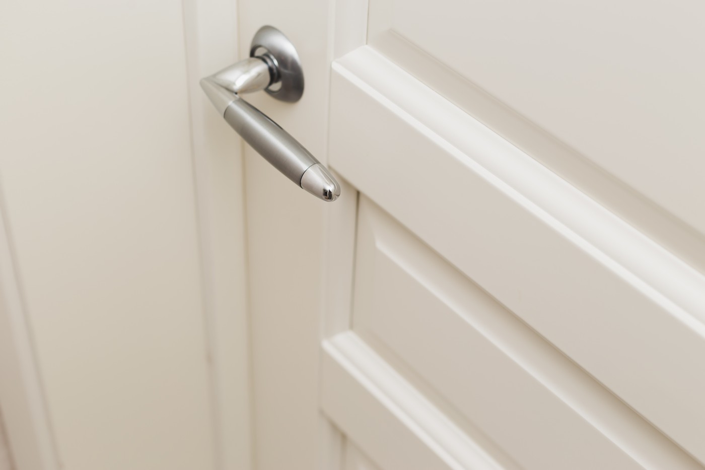 Classic white wooden milled door with chrome handle. White Scandinavian interior