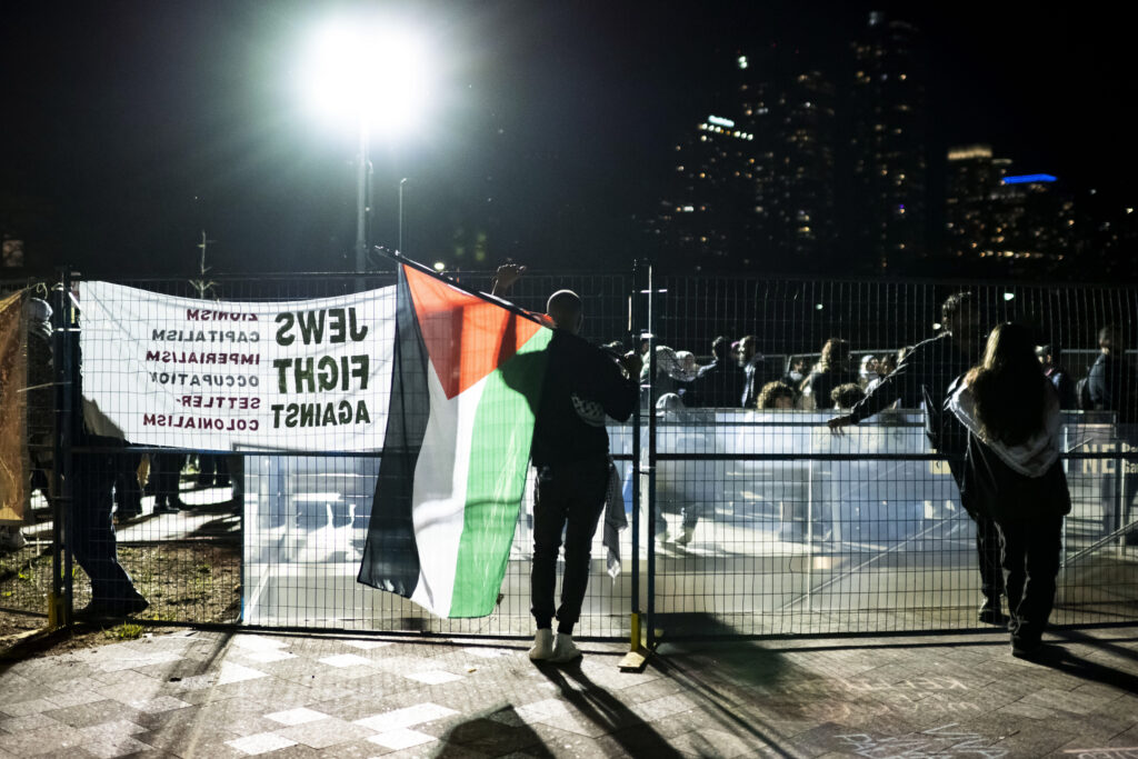 A demonstrator talks to supporters outside the perimeter of a pro-Palestinian encampment set up on the University of Toronto campus in Toronto, Thursday, May 2, 2024. (Christopher Katsarov/The Canadian Press via AP)