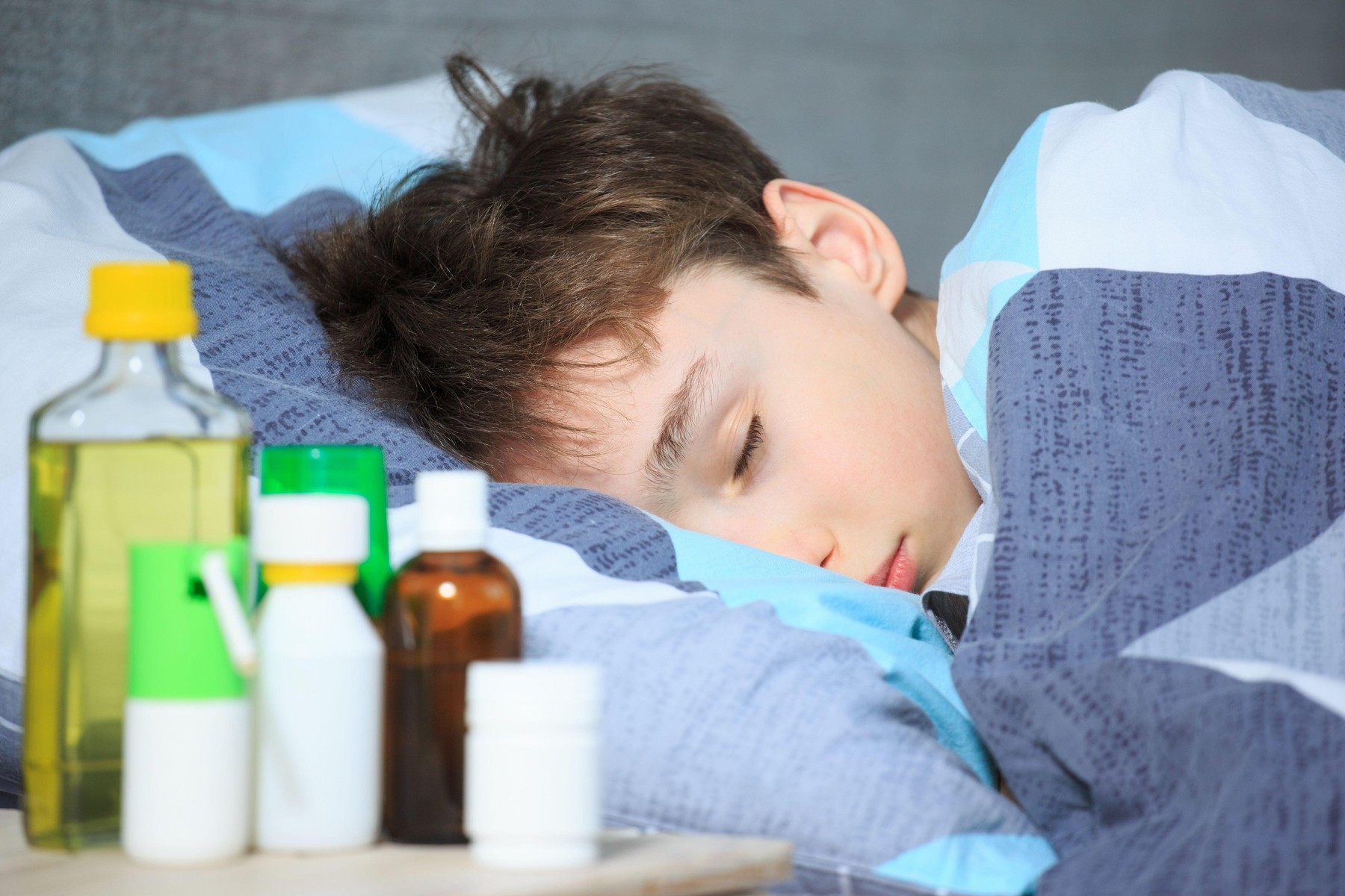 sick boy lying in bed with a thermometer in mouth Bolesna deca koronavirus dete