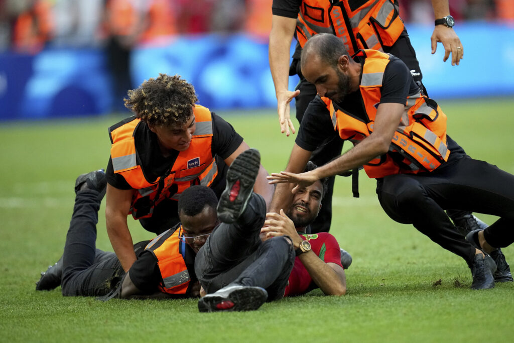 A spontaneous man is chased by security personnel during a men's semifinal soccer match between Morocco and Spain at the 2024 Summer Olympics, Monday, Aug. 5, 2024, at Marseille Stadium in Marseille, France. (AP Photo/Daniel Cole)