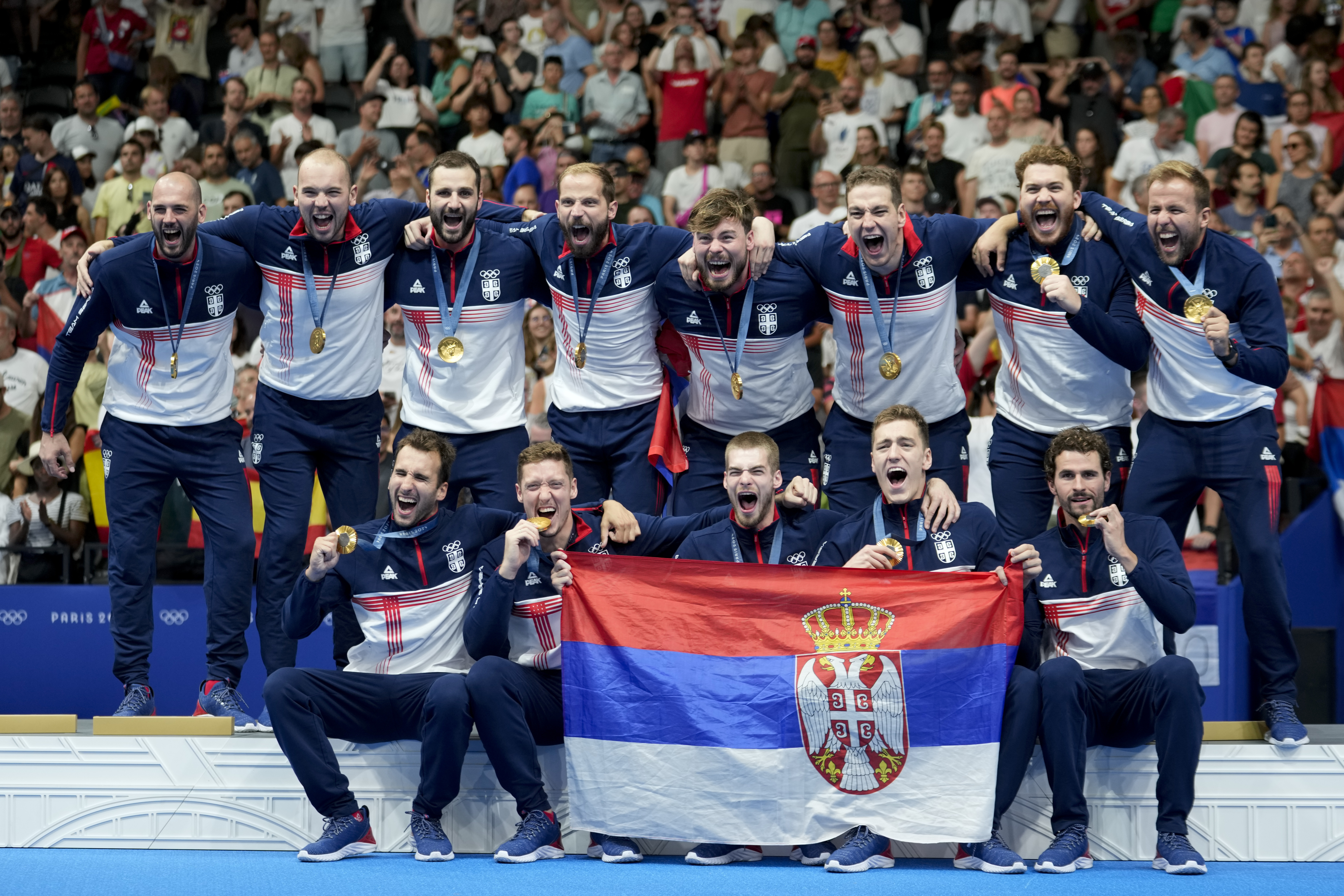 Serbia's team pose on the podium after winning gold in the men's water polo at the 2024 Summer Olympics, Sunday, Aug. 11, 2024, in Paris, France. (AP Photo/Luca Bruno)