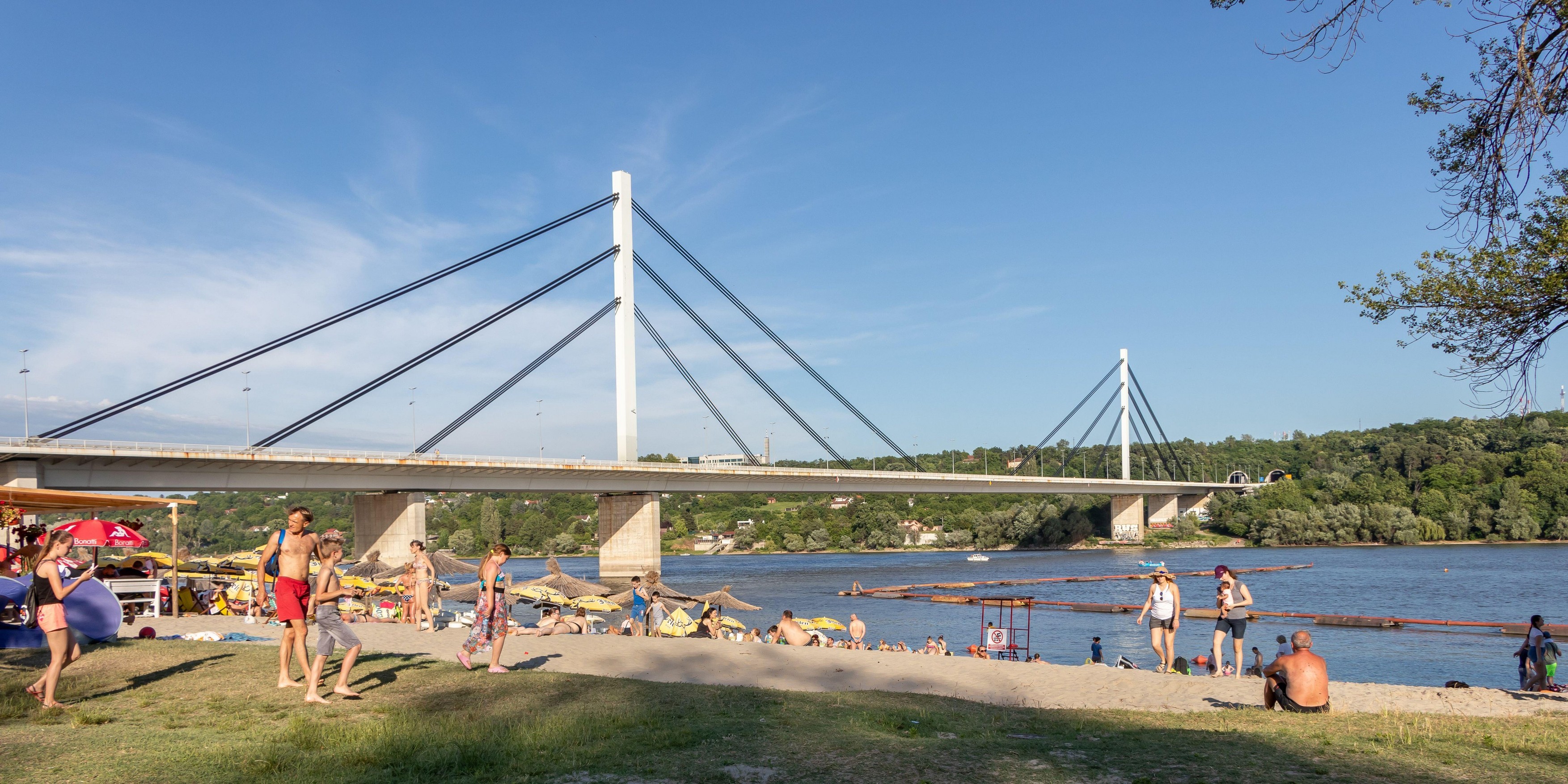 Novi Sad, Serbia - June 14, 2020: People enjoy on a beach (Strand) on a Danube river, view at Liberty Bridge (Most Slobode) in Novi Sad, Serbia