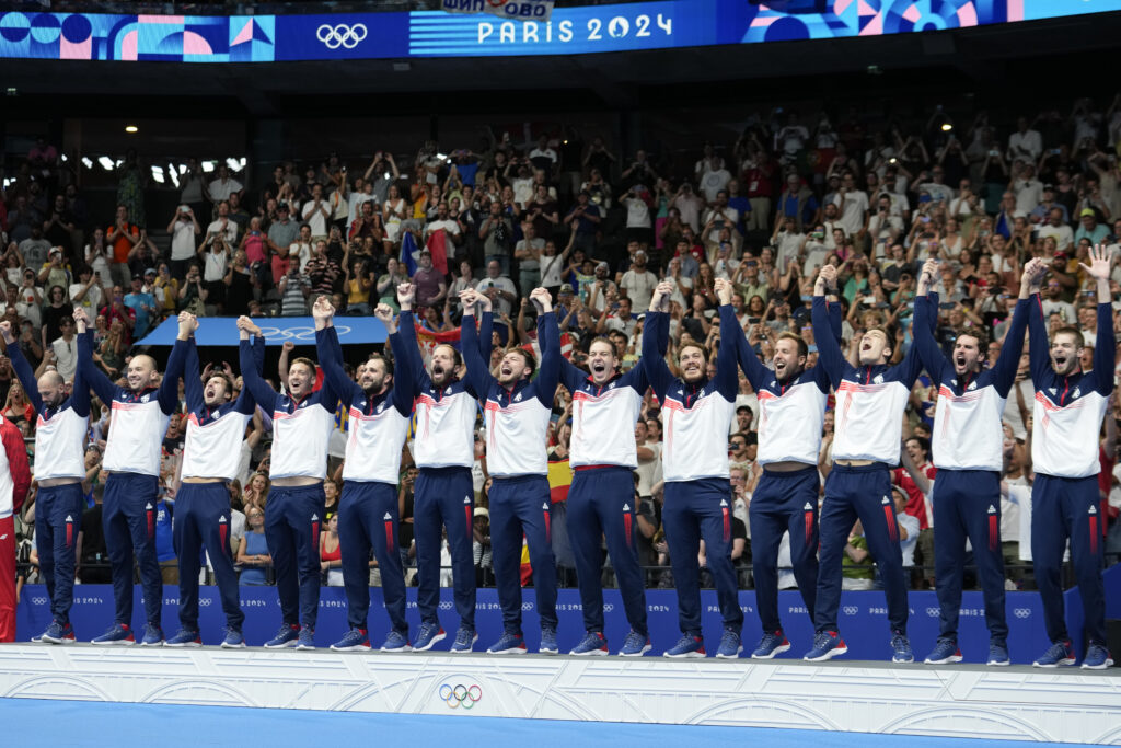 Serbia's team celebrates on the podium after winning gold in the men's water polo at the 2024 Summer Olympics, Sunday, Aug. 11, 2024, in Paris, France. (AP Photo/Luca Bruno)