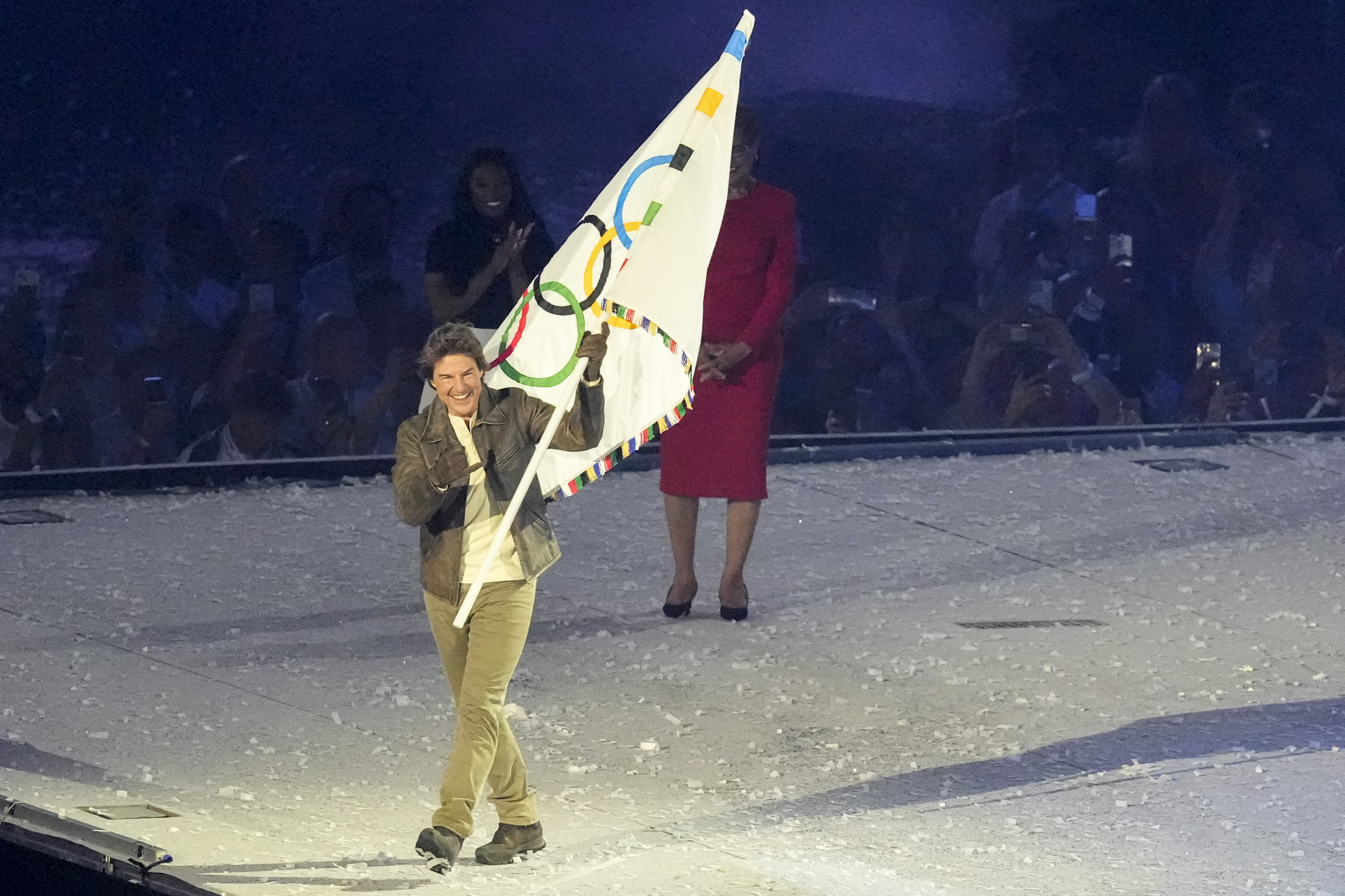 Tom Cruise holds the Olympic flag during the 2024 Summer Olympics closing ceremony at the Stade de France, Sunday, Aug. 11, 2024, in Saint-Denis, France. (AP Photo/Martin Meissner)