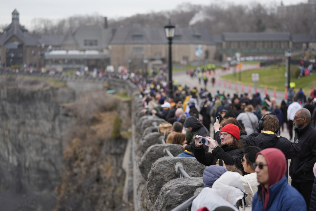 People gather under overcast skies in anticipation of watching the total solar eclipse from Niagara Falls, Ontario, Monday, April 8, 2024. (AP Photo/Matt Rourke)