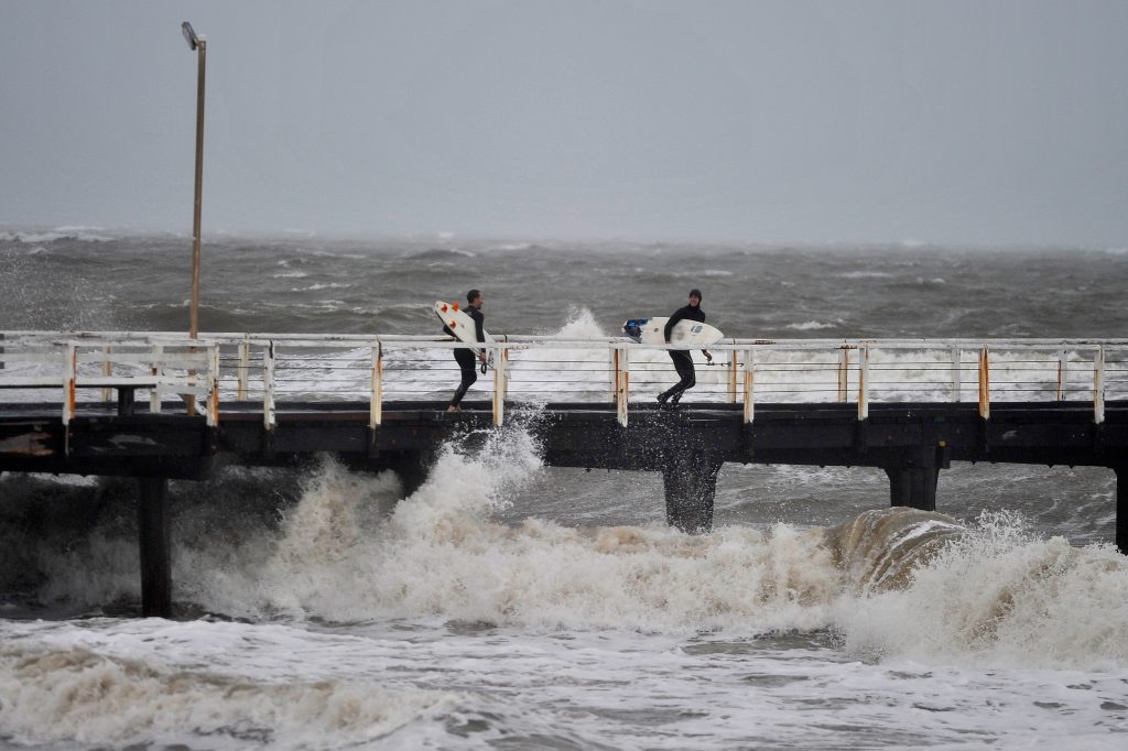 epa05561423 Surfers on a jetty look to jump into the waves that have been created by a storm front on Adelaide metropolitan beaches, South Australia, Australia, 29 September 2016.  EPA/DAVID MARIUZ AUSTRALIA AND NEW ZEALAND OUT