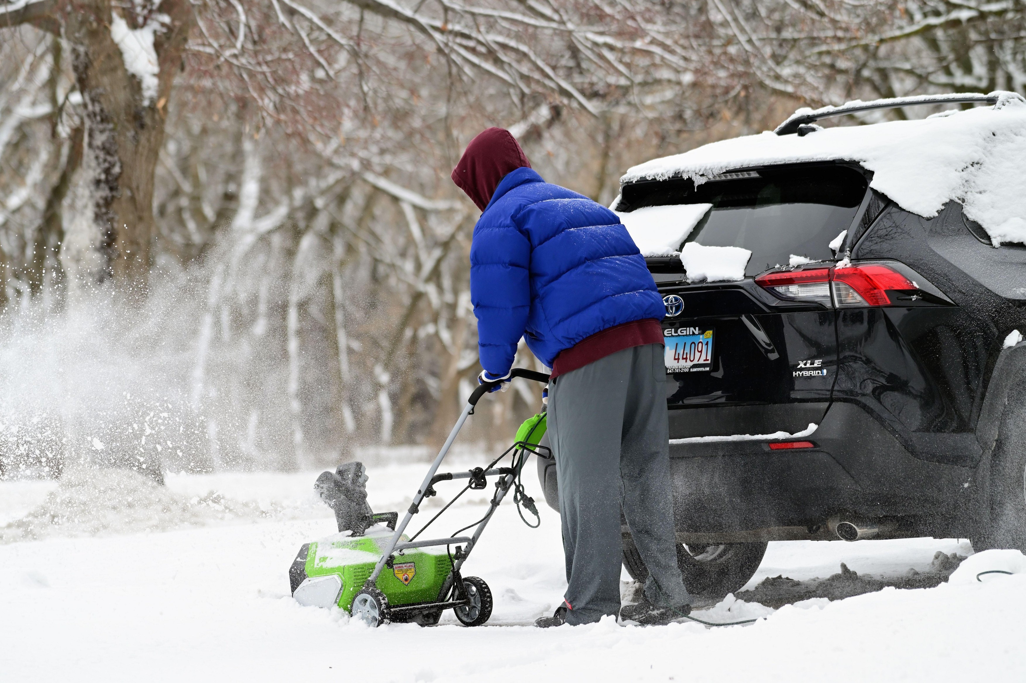 Streamwood, Illinois, USA. A man works to clear snow from his driveway following a winter storm in the Chicago suburbs.