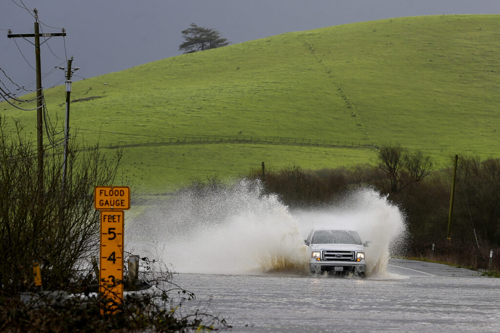 A truck drives through a flooded Valley Ford Road on Monday, Feb. 19, 2024, in Bloomfield, Calif. (Christopher Chung/The Press Democrat via AP)