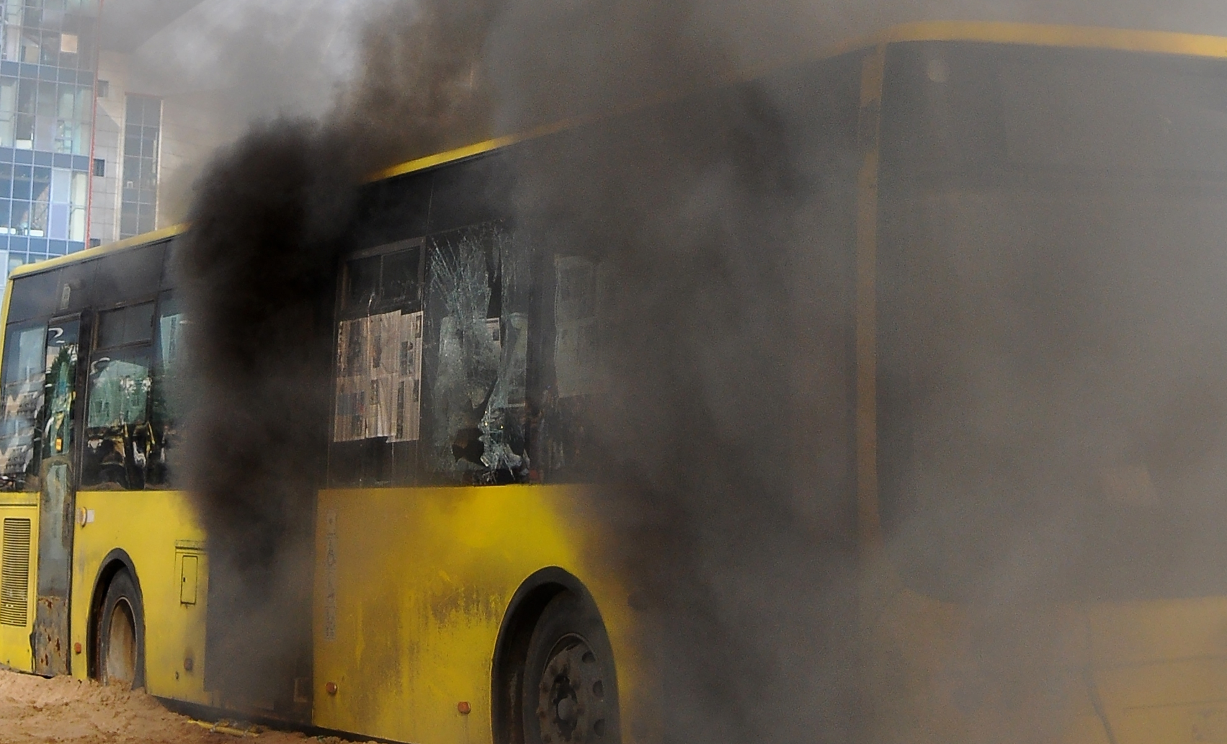 A city bus burns with black smoke on the beach on a bright sunny day, Public transit bus had caught fire
