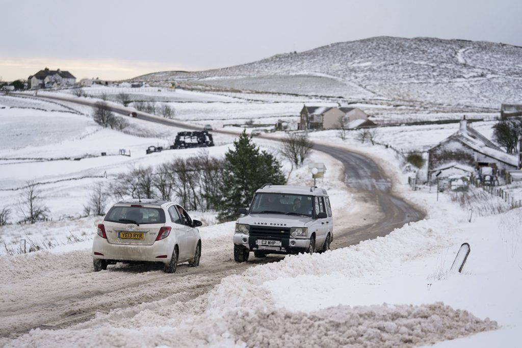 Vehicles travel tentatively on the snow-covered A53 close to Buxton in Derbyshire, amid freezing conditions in the aftermath of Storm Arwen, England, Sunday, Nov. 28, 2021.  (Jacob King/PA via AP)