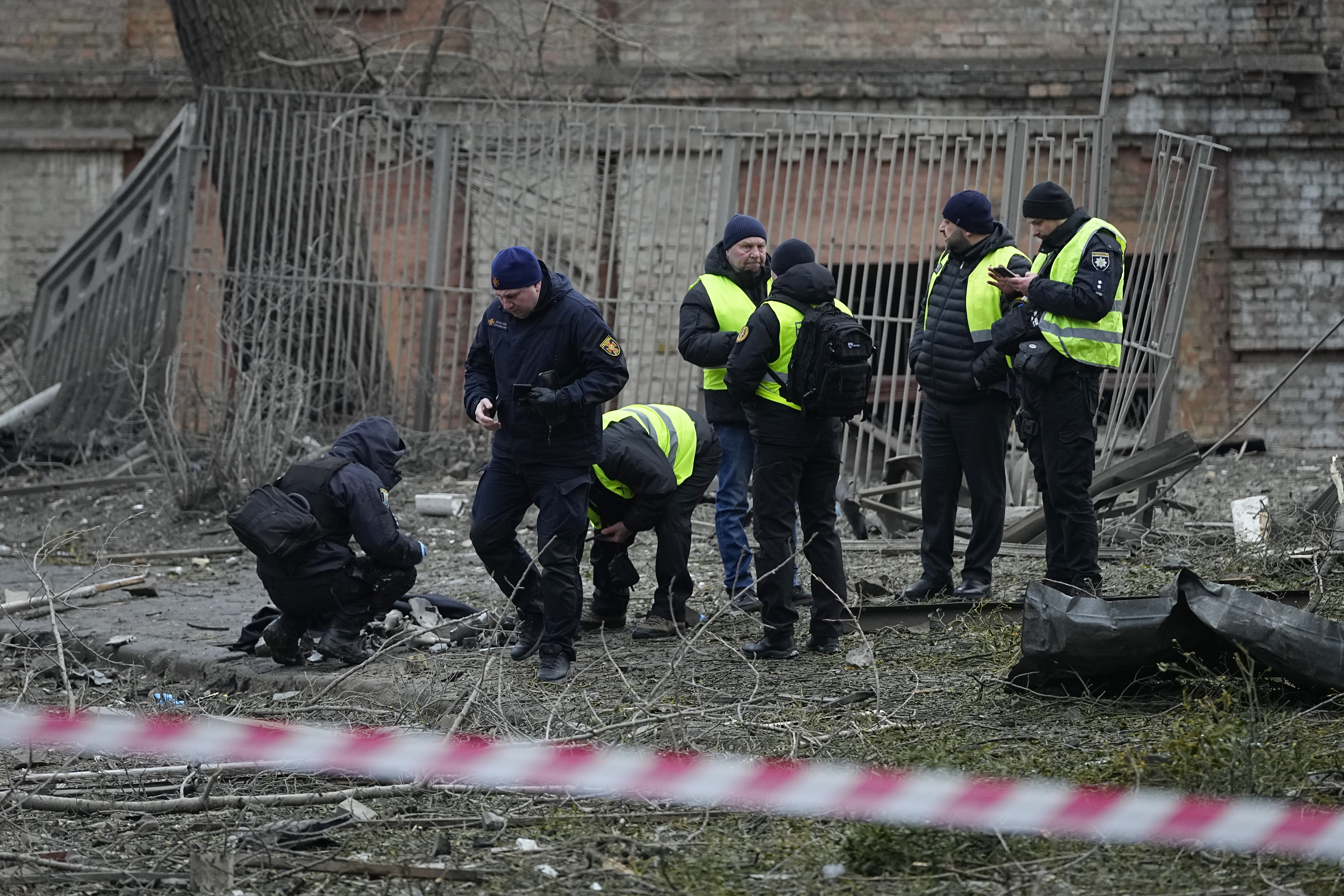 Police inspect a yard near building damaged by a Russian attack in Kyiv, Ukraine, Tuesday, Jan. 23, 2024. (AP Photo/Efrem Lukatsky)