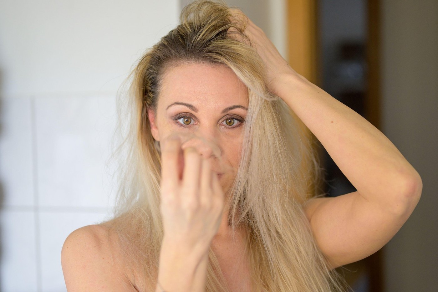 Shocked forty year old woman looking at a tuft of hair in her hand in a hair loss concept