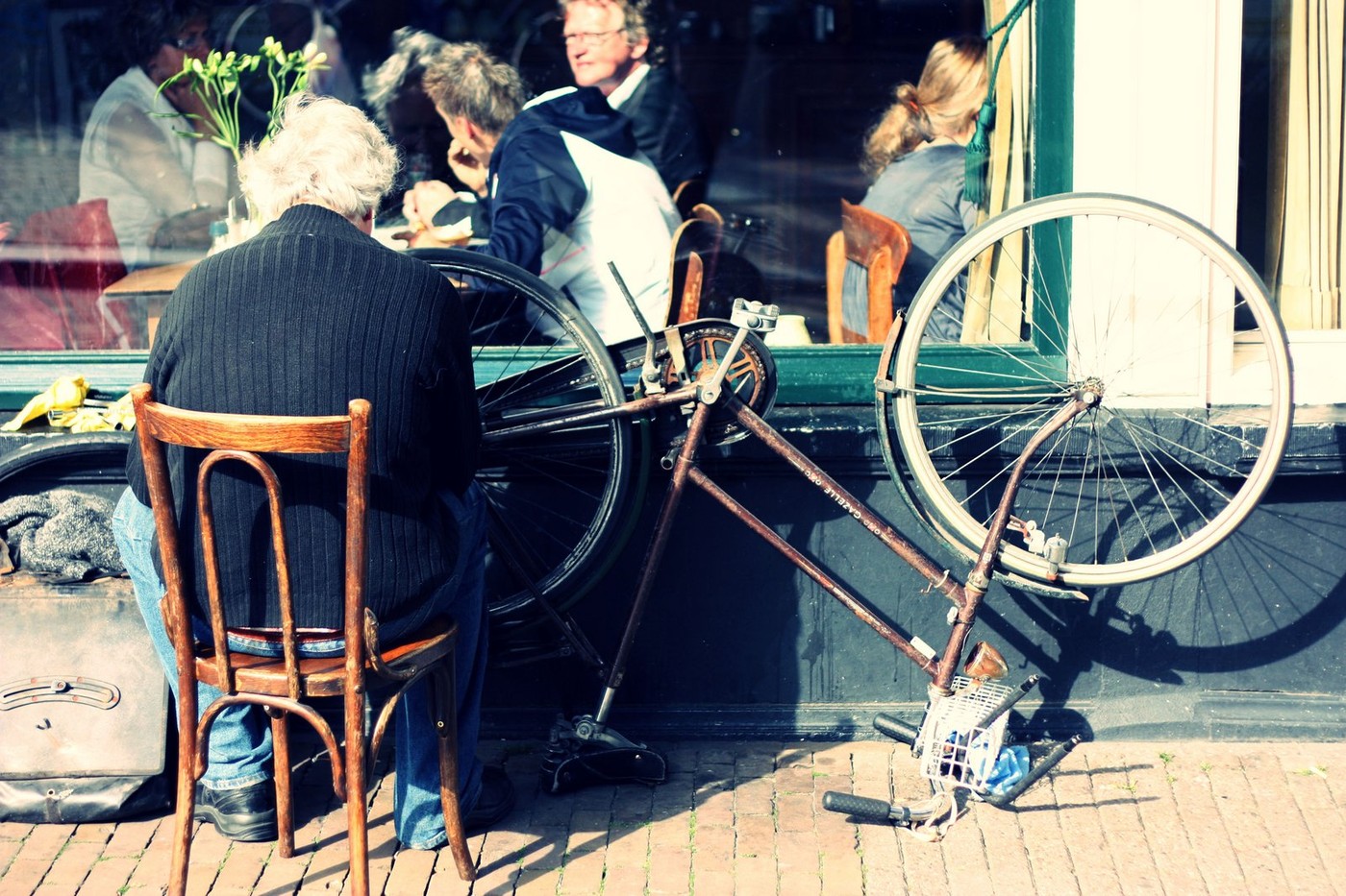 An old man repairing a punctured bicycle tyre.