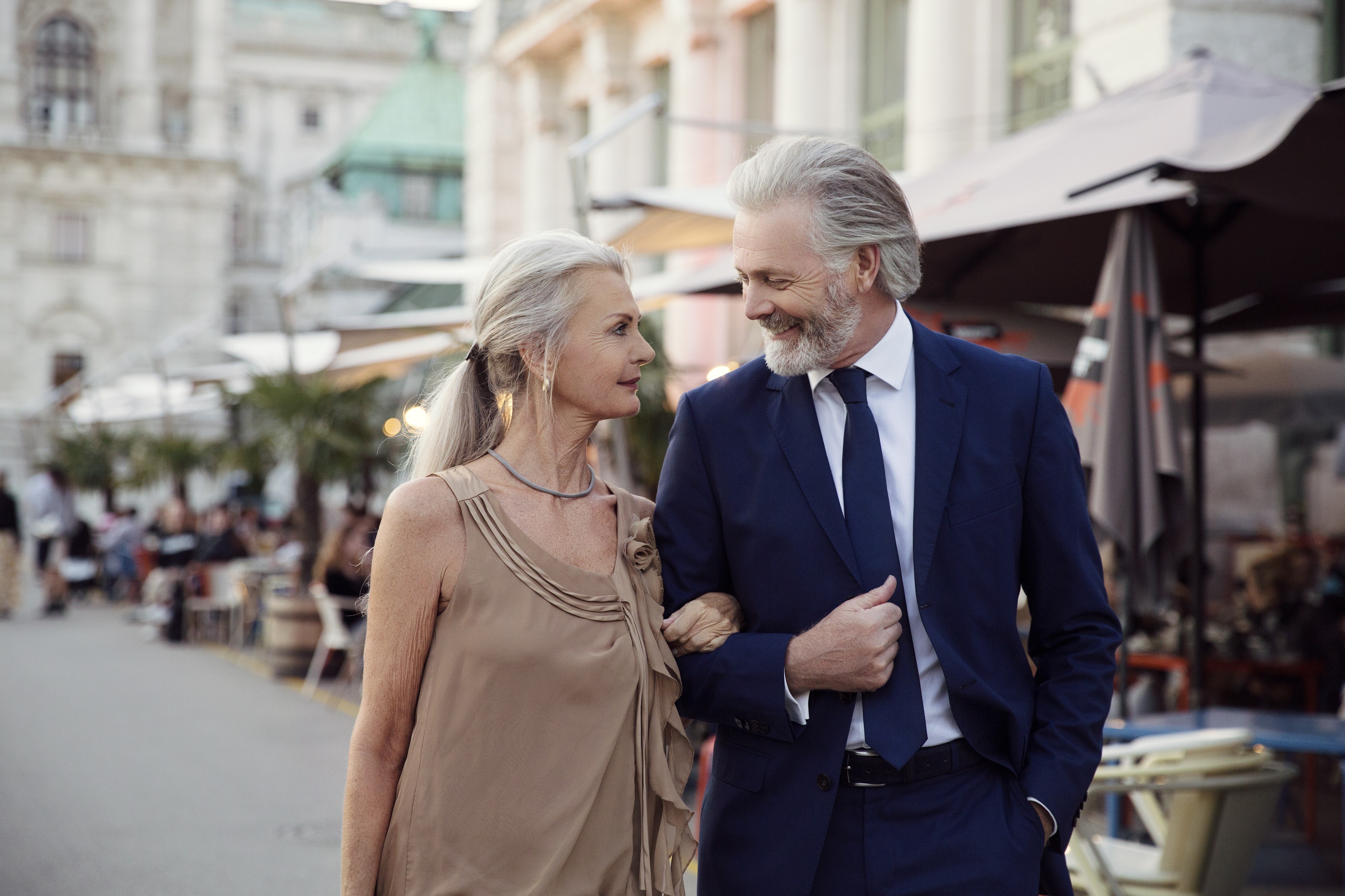 A couple walk arm in arm along a street with bars and market stalls in Vienna.