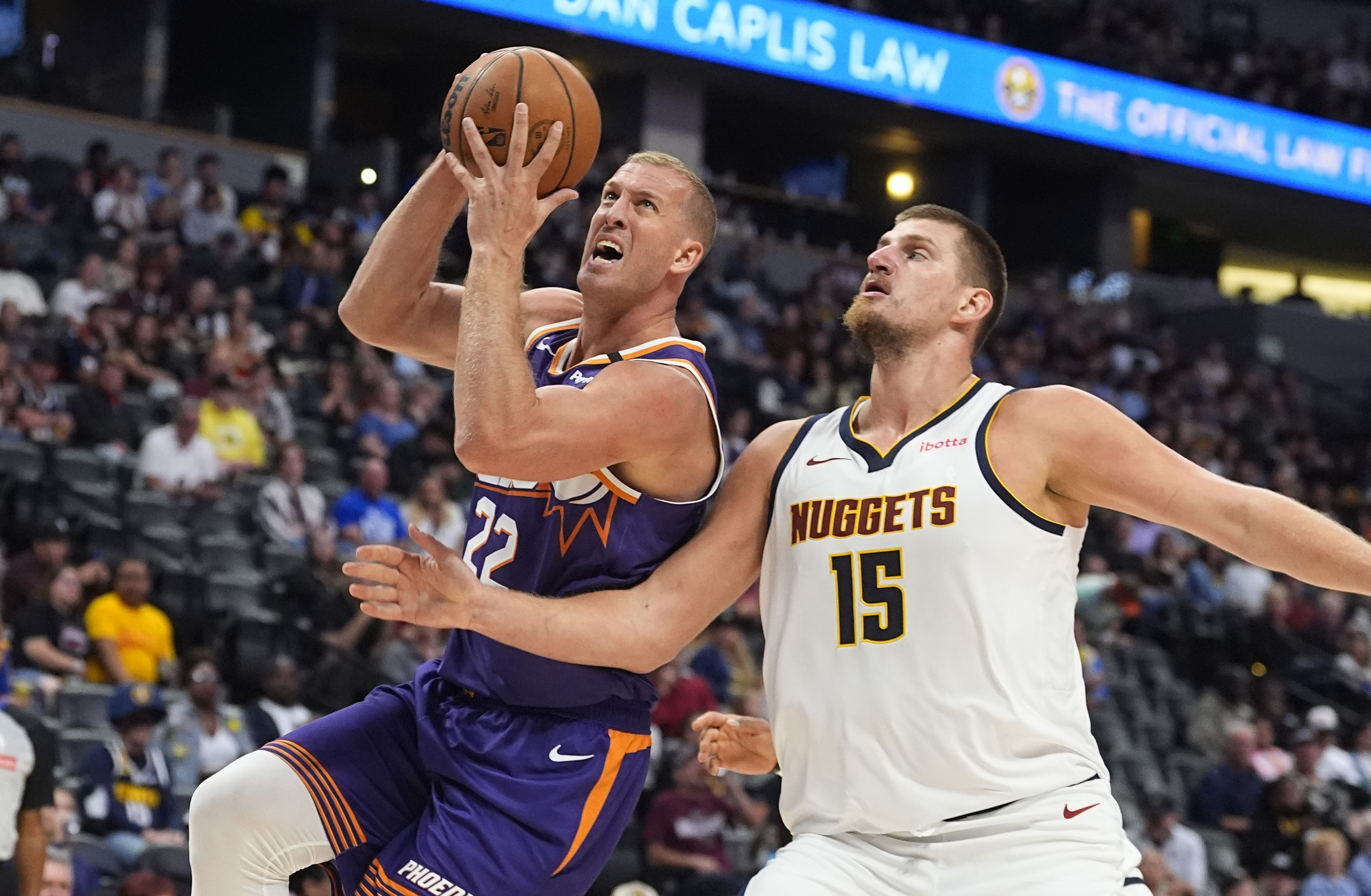 Phoenix Suns center Mason Plumlee, left, drives to the rim past Denver Nuggets center Nikola Jokic in the second half of an NBA preseason game Sunday, Oct. 13, 2024, in Denver. (AP Photo/David Zalubowski)