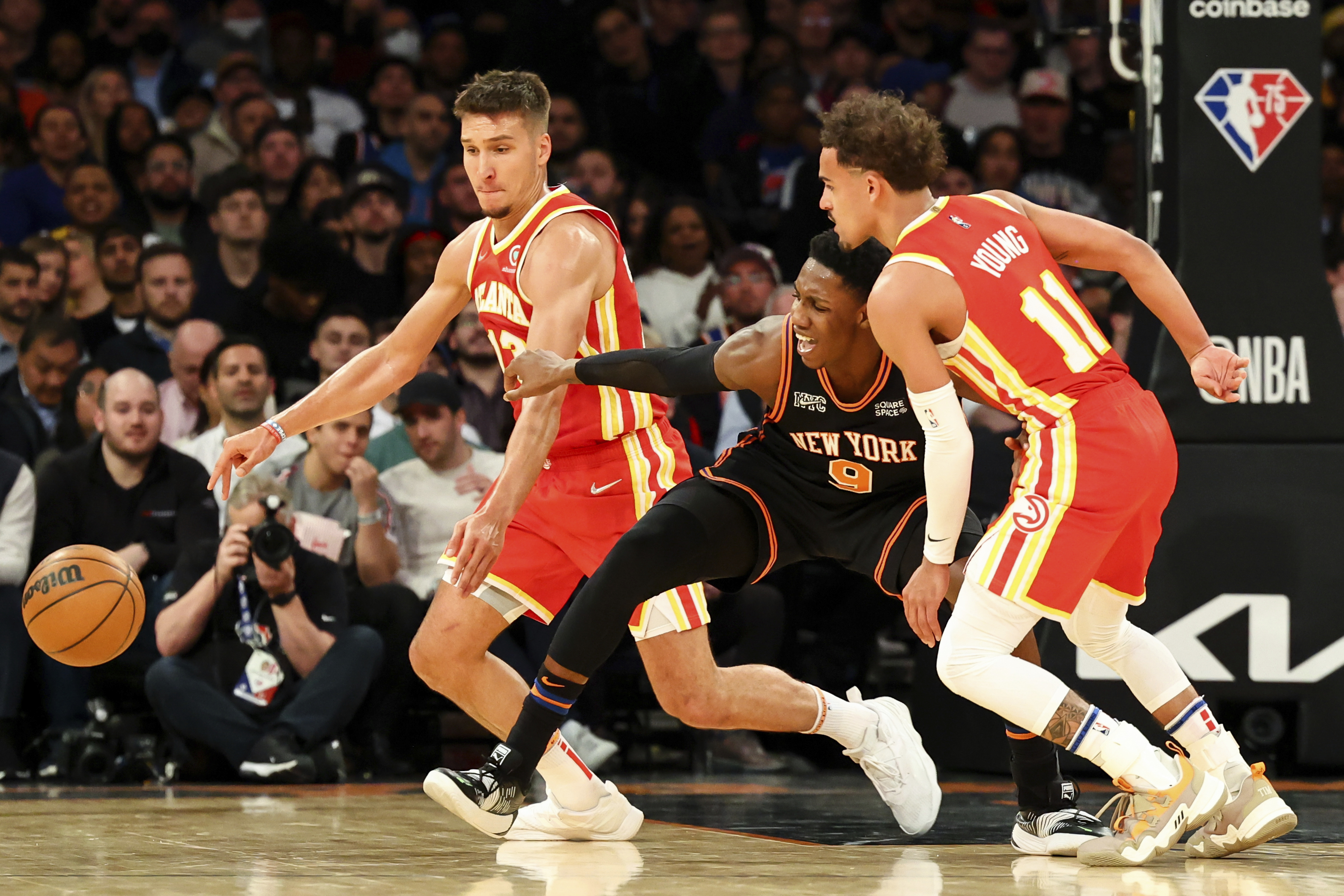 Atlanta Hawks guard Bogdan Bogdanovic (13) and guard Trae Young (11) steal the ball from New York Knicks guard RJ Barrett (9) during the second half of an NBA basketball game, Tuesday, March 22, 2022, in New York. (AP Photo/Jessie Alcheh)