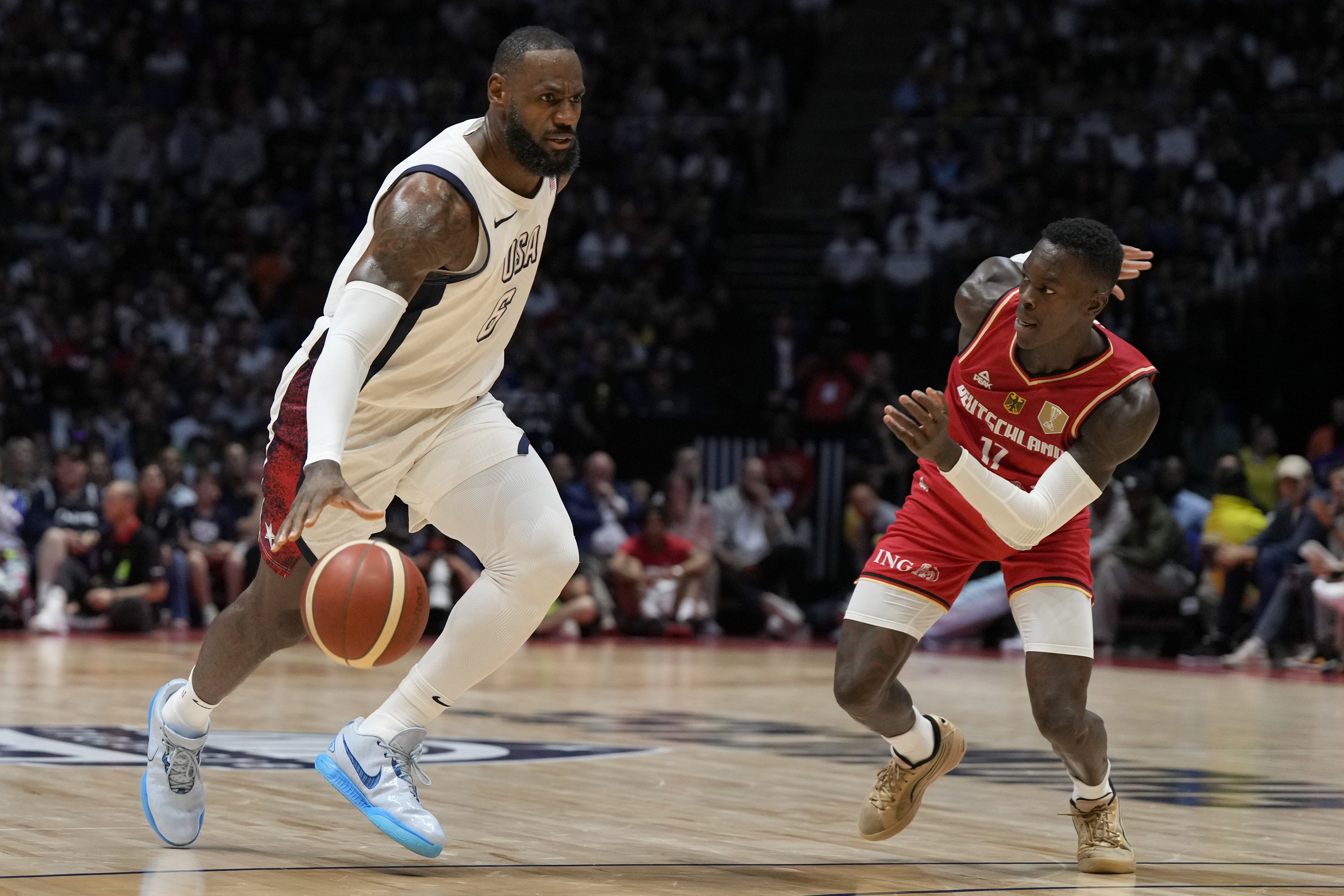 United States' forward LeBron James, left, and Germany's guard Dennis Schroeder challenge for the ball during an exhibition basketball game between the United States and Germany at the O2 Arena in London, Monday, July 22, 2024. (AP Photo/Alastair Grant)