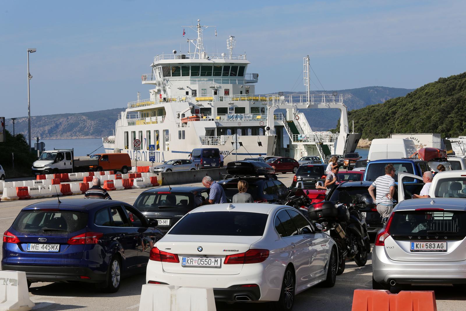 19.06.2019., Valbiska, Krk - Turisti u trajektnom pristanistu cekaju Jadrolinijin trajekt Kornati koji plovi na relaciji Valbiska (Krk) - Merag (Cres). Photo: Goran Kovacic/PIXSELL