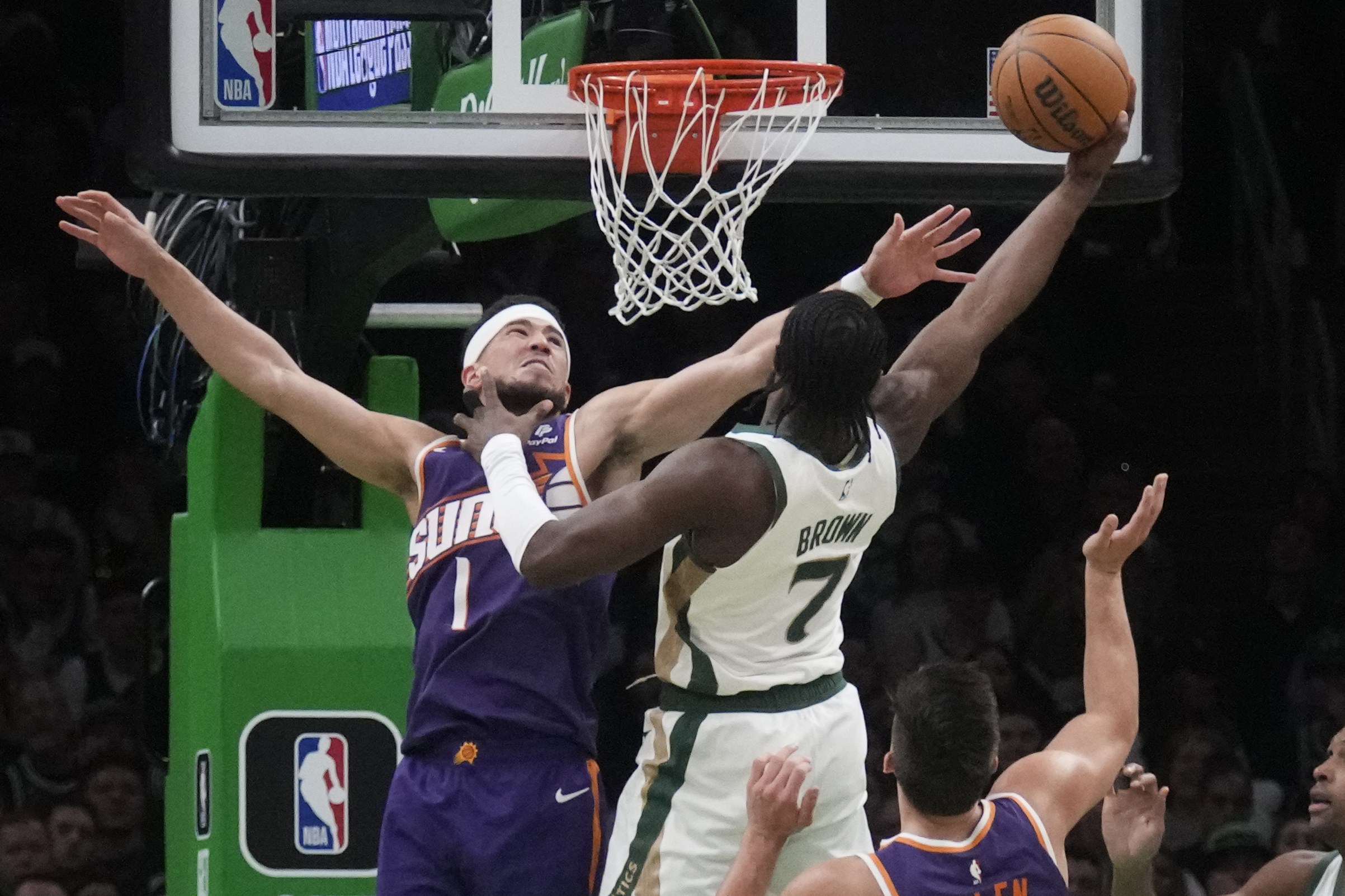 Phoenix Suns guard Devin Booker (1) tries to block a shot by Boston Celtics guard Jaylen Brown (7) during the second half of an NBA basketball game, Thursday, March 14, 2024, in Boston. (AP Photo/Charles Krupa)