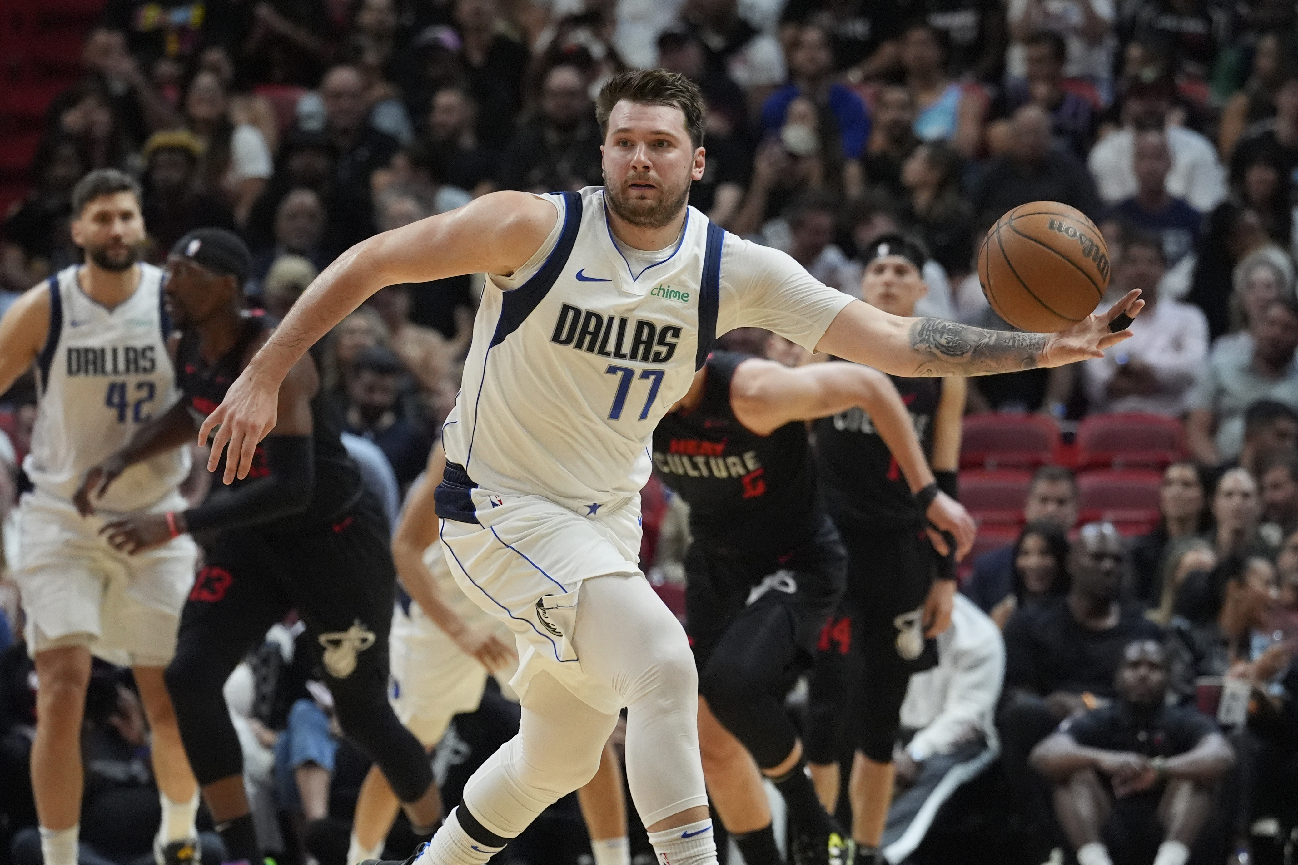 Dallas Mavericks guard Luka Doncic (77) grabs a loose ball during the first half of an NBA basketball game against the Miami Heat, Wednesday, April 10, 2024, in Miami. (AP Photo/Marta Lavandier)