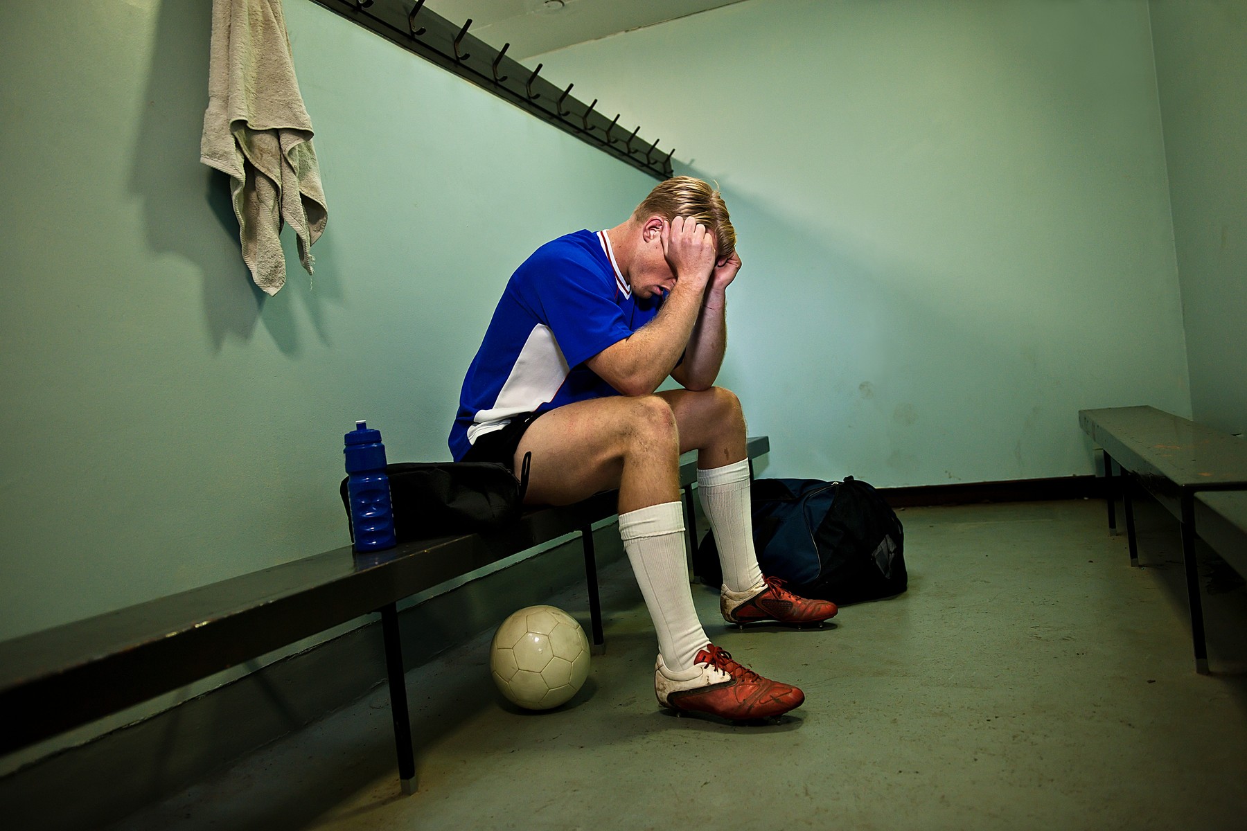 Soccer player in changing room with head in hands