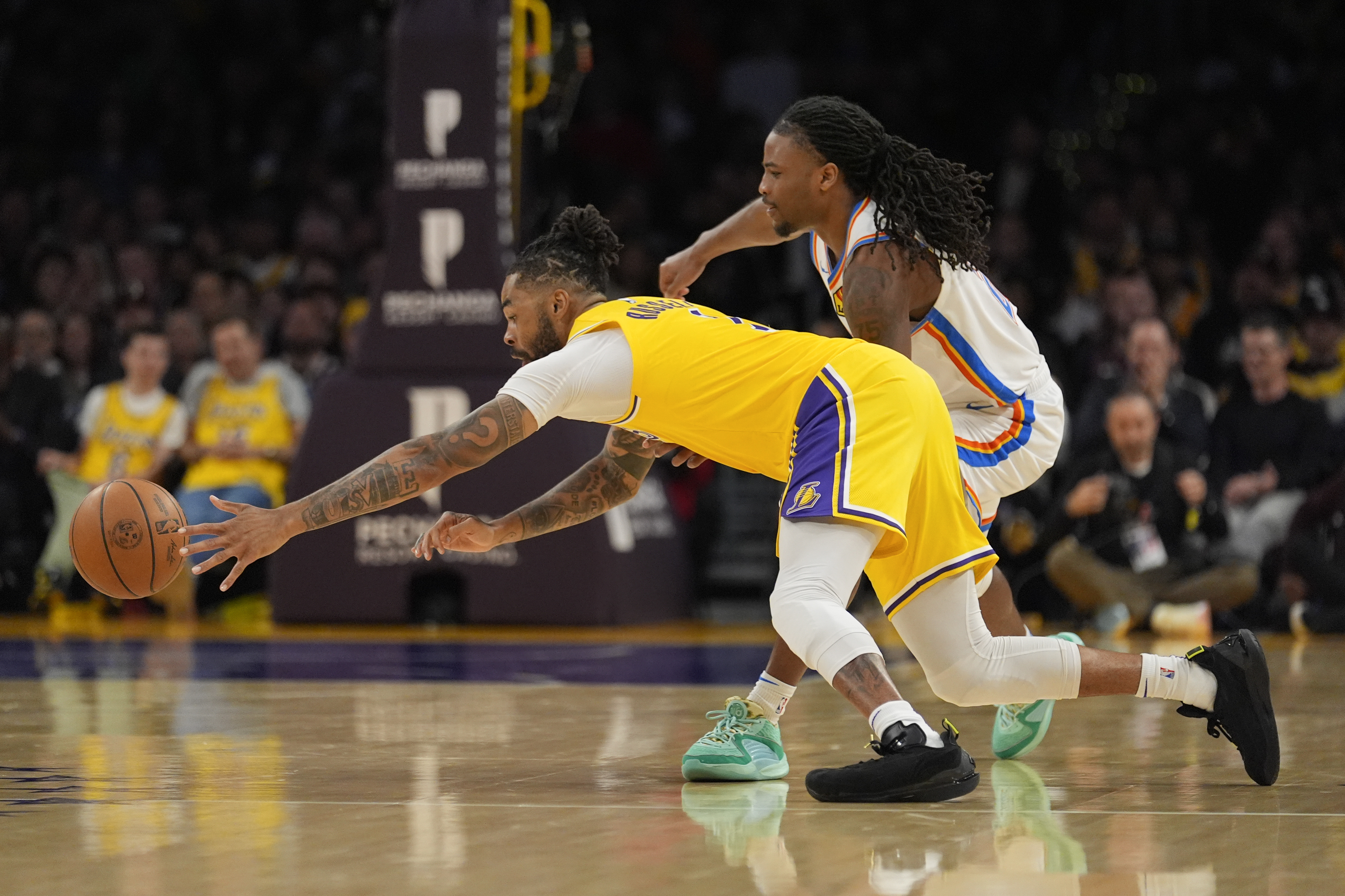Los Angeles Lakers guard D'Angelo Russell, left, reaches for a rebound in front of Oklahoma City Thunder guard Cason Wallace during the second half of an NBA basketball game Monday, March 4, 2024, in Los Angeles. (AP Photo/Marcio Jose Sanchez)