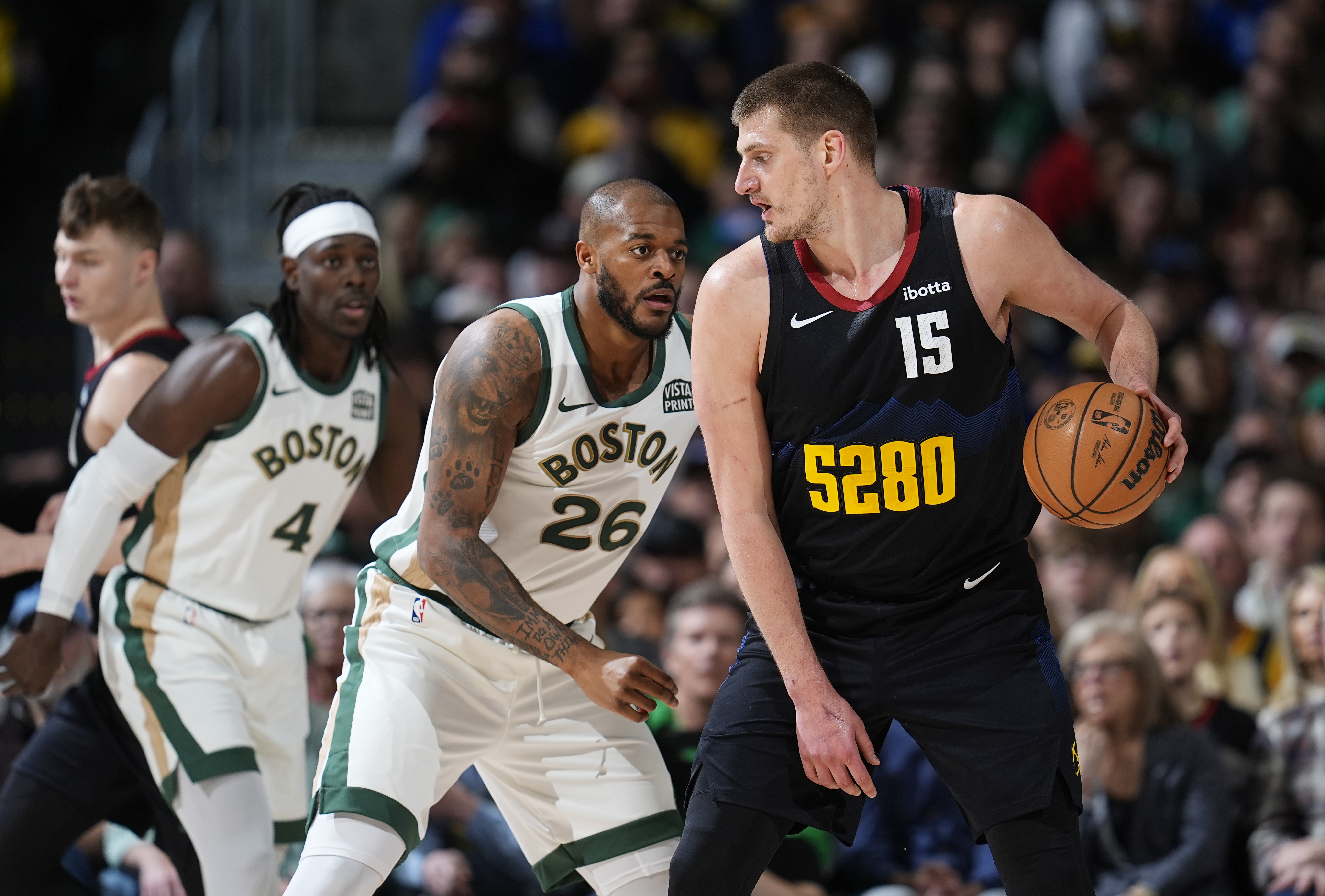 Denver Nuggets center Nikola Jokic, right, looks to pass the ball as Boston Celtics forward Xavier Tillman, center, and guard Jrue Holiday defend in the first half of an NBA basketball game Thursday, March 7, 2024, in Denver. (AP Photo/David Zalubowski)