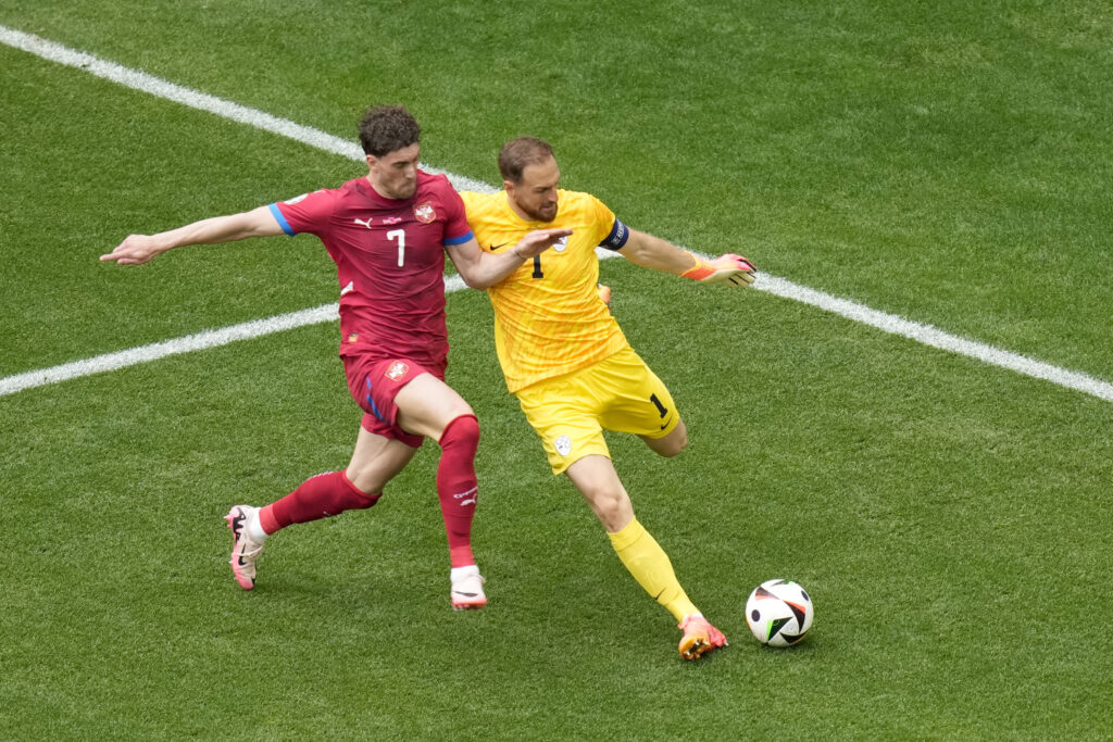 Slovenia's goalkeeper Jan Oblak, right, clears the ball away from Serbia's Dusan Vlahovic during a Group C match between Slovenia and Serbia at the Euro 2024 soccer tournament in Munich, Germany, Thursday, June 20, 2024. (AP Photo/Ariel Schalit)