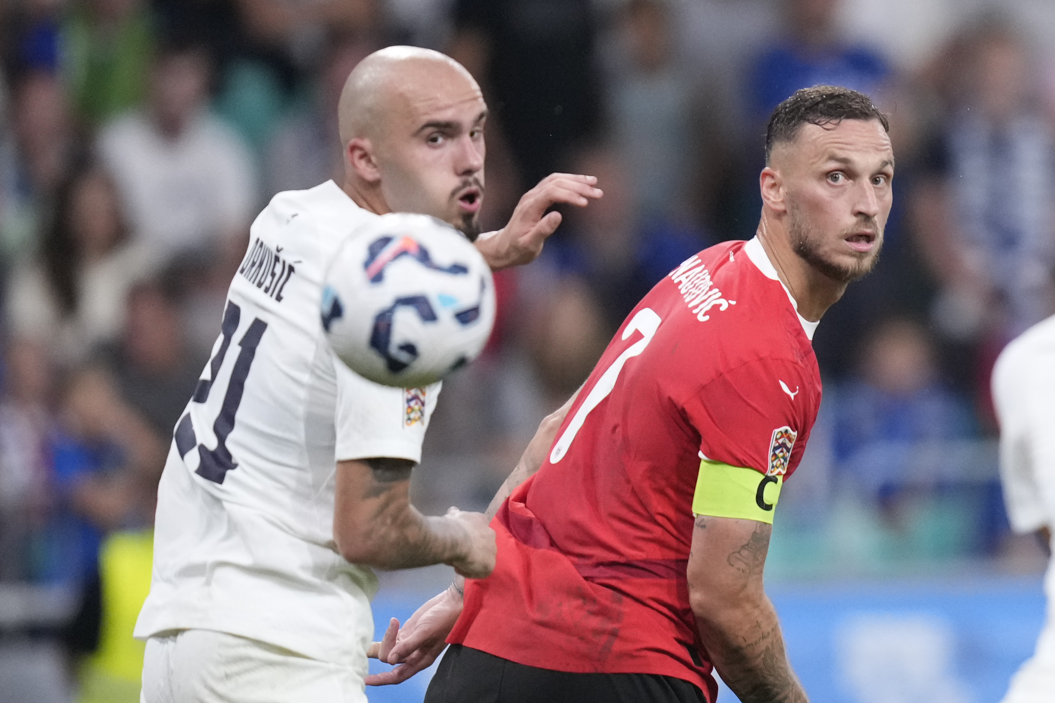 Slovenia's Vanja Drkusic, left, and Austria's Marko Arnautovic look at the ball during the UEFA Nations League soccer match between Slovenia and Austria at the Stozice stadium in Ljubljana, Slovenia, Friday, Sept. 6, 2024. (AP Photo/Darko Bandic)