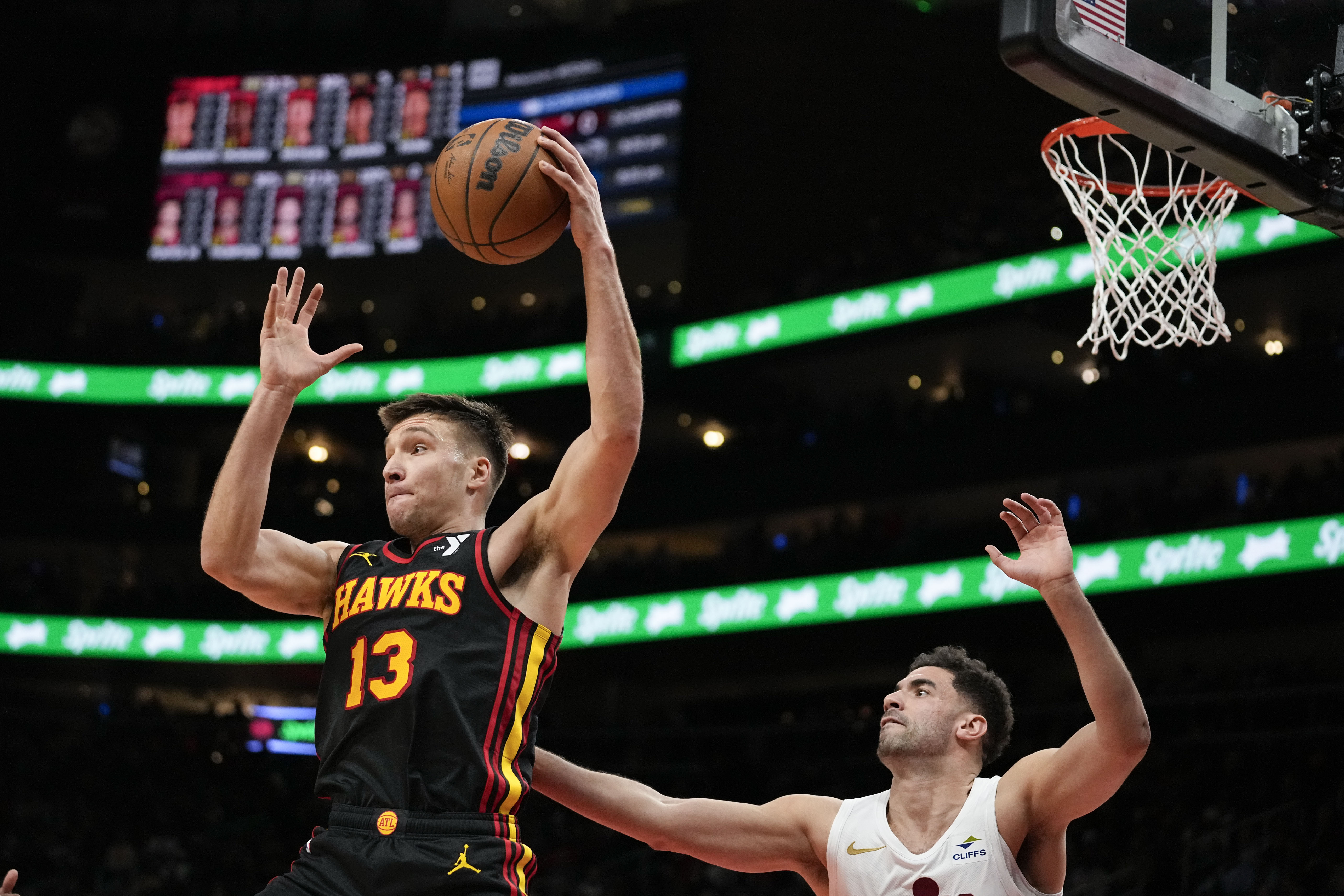 Atlanta Hawks guard Bogdan Bogdanovic (13) rebounds the ball against Cleveland Cavaliers forward Georges Niang (20) in the first half of an NBA basketball game, Saturday, Jan. 20, 2024, in Atlanta. (AP Photo/Brynn Anderson)