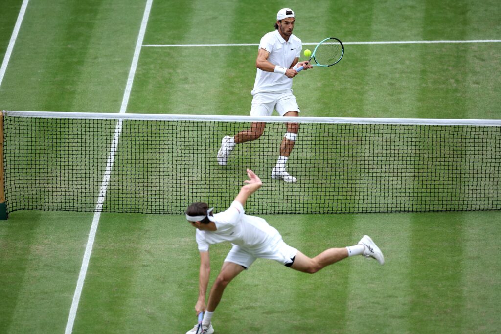 epa11470614 Lorenzo Musetti (top) of Italy in action during the Men's quarterfinal match against Taylor Fritz of the USA at the Wimbledon Championships, Wimbledon, Britain, 10 July 2024.  EPA-EFE/ADAM VAUGHAN  EDITORIAL USE ONLY