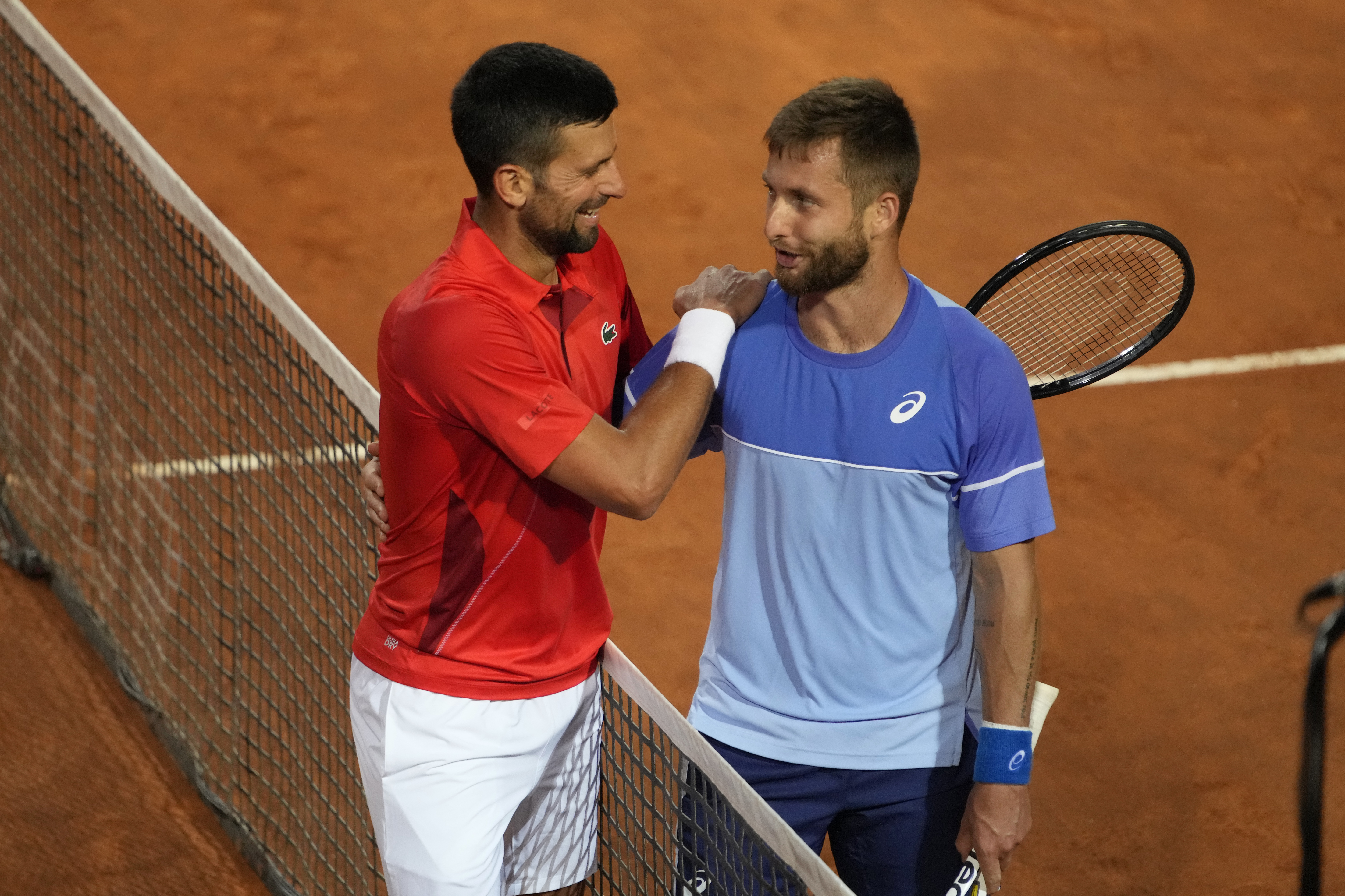 Serbia's Novak Djokovic, left, talks with France's Corentin Moutet at the end of their match at the Italian Open tennis tournament in Rome, Friday, May 10, 2024. Djokovic won. (AP Photo/Alessandra Tarantino)