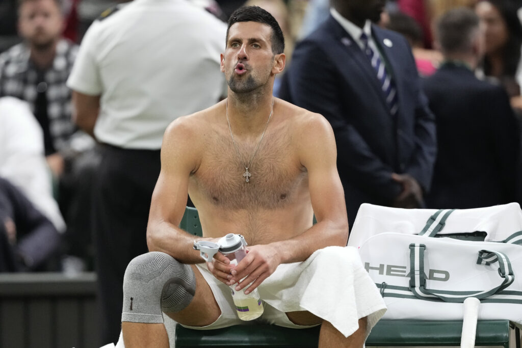 Novak Djokovic of Serbia reacts in his chair during a break in his fourth round match against Hulger Rune of Denmark at the Wimbledon tennis championships in London, Monday, July 8, 2024. (AP Photo/Kirsty Wigglesworth)