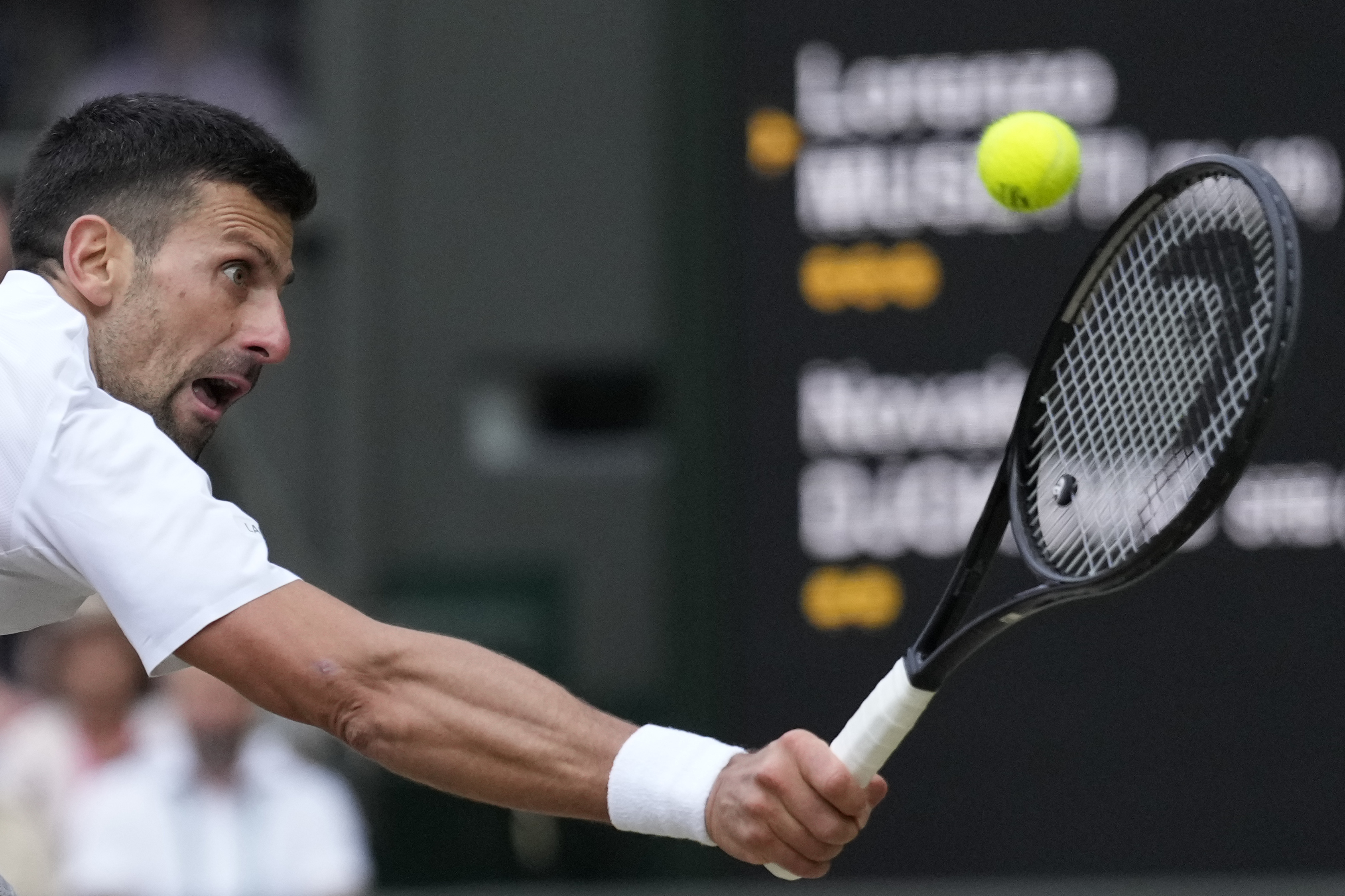 Novak Djokovic of Serbia plays a backhand Lorenzo Musetti of Italy during their semifinal match at the Wimbledon tennis championships in London, Friday, July 12, 2024. (AP Photo/Mosa'ab Elshamy)