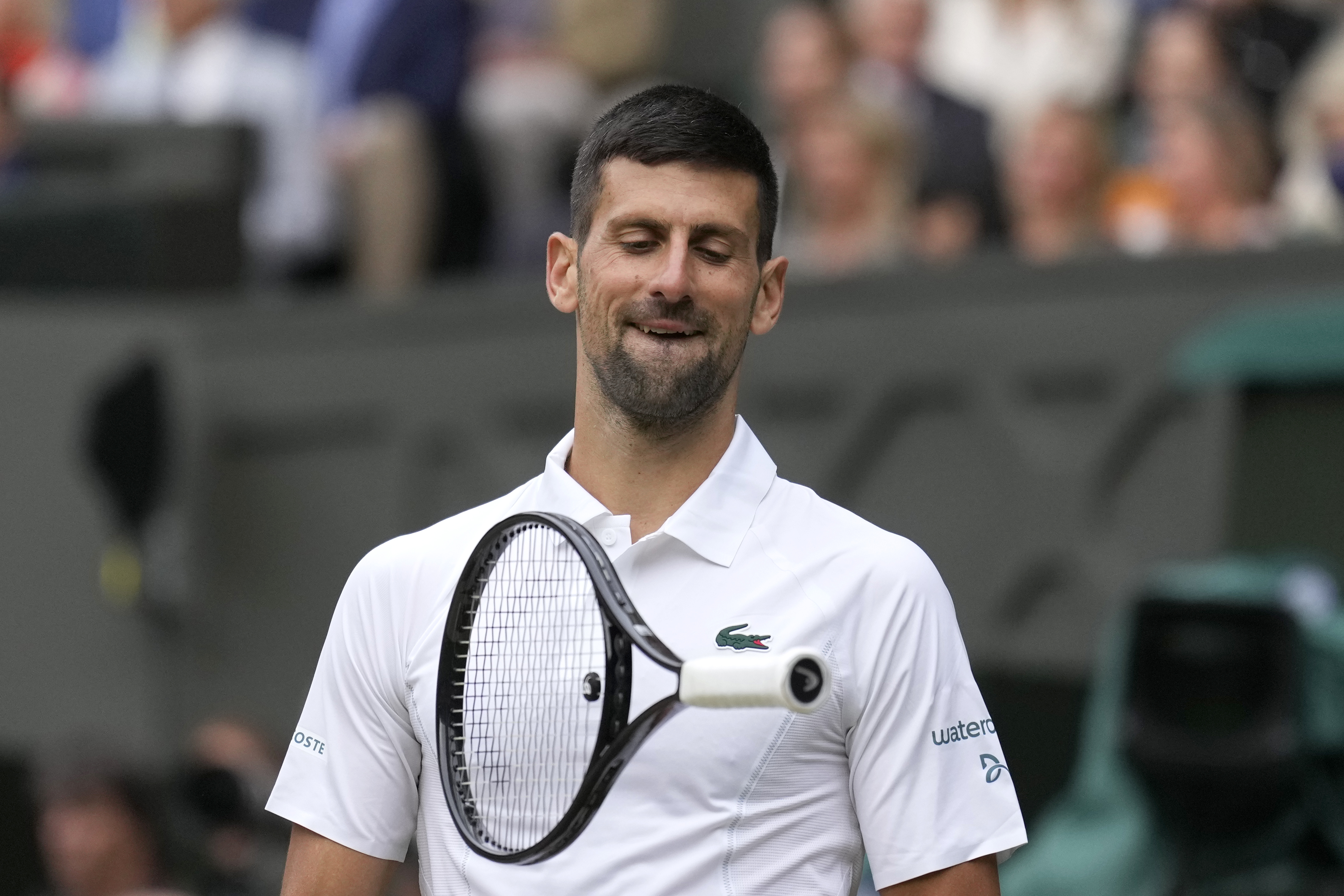 Novak Djokovic of Serbia reacts by throwing his racket in the air as he plays against Lorenzo Musetti of Italy during their semifinal match at the Wimbledon tennis championships in London, Friday, July 12, 2024. (AP Photo/Mosa'ab Elshamy)