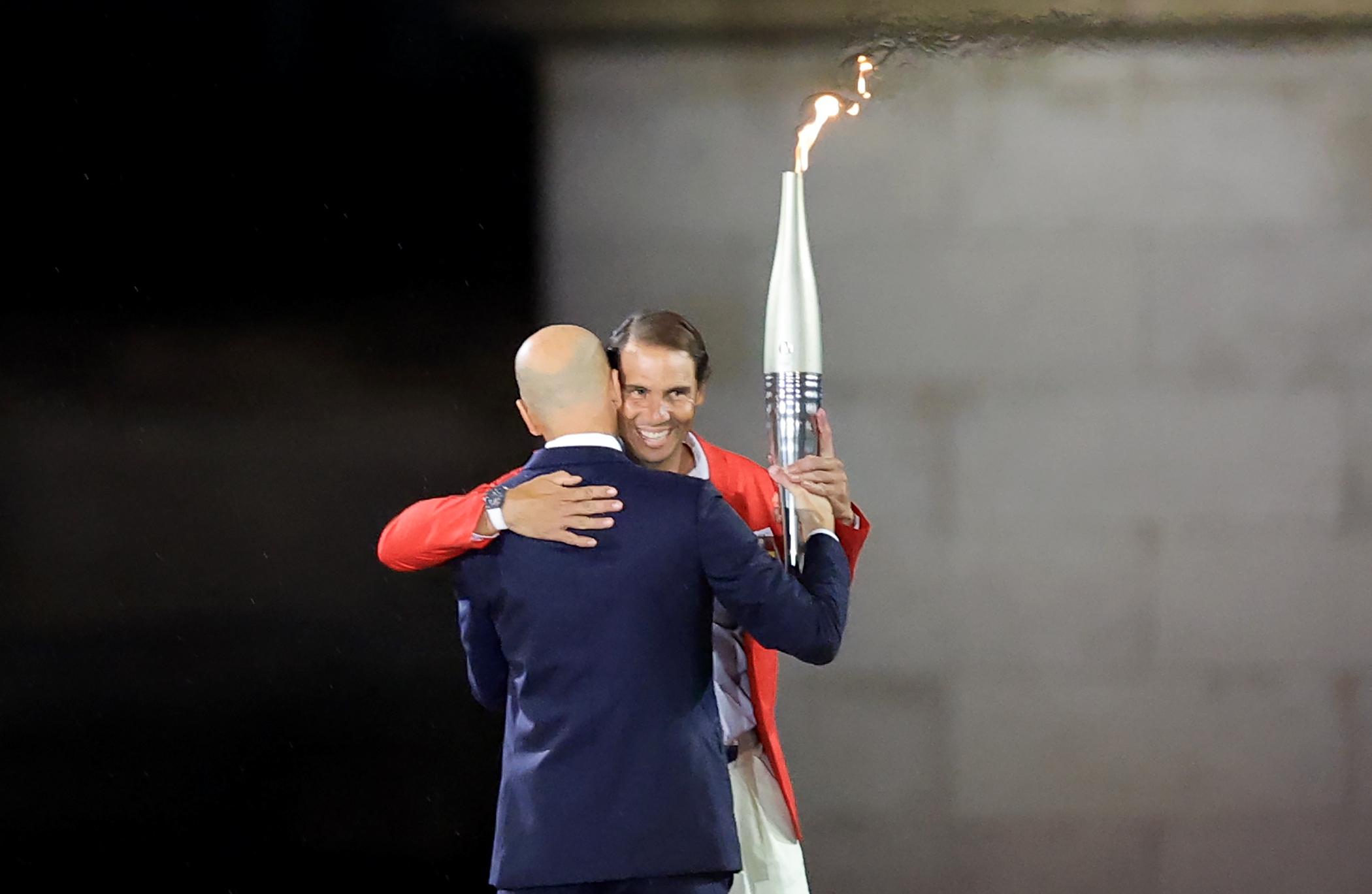 epa11498117 Former French soccer Zinedine Zidane (L) hands the Olympic flame to Spanish tennis player Rafael Nadal in the Trocadero during the Opening Ceremony of the Paris 2024 Olympic Games, in Paris, France, 26 July 2024.  EPA-EFE/MARTIN DIVISEK
