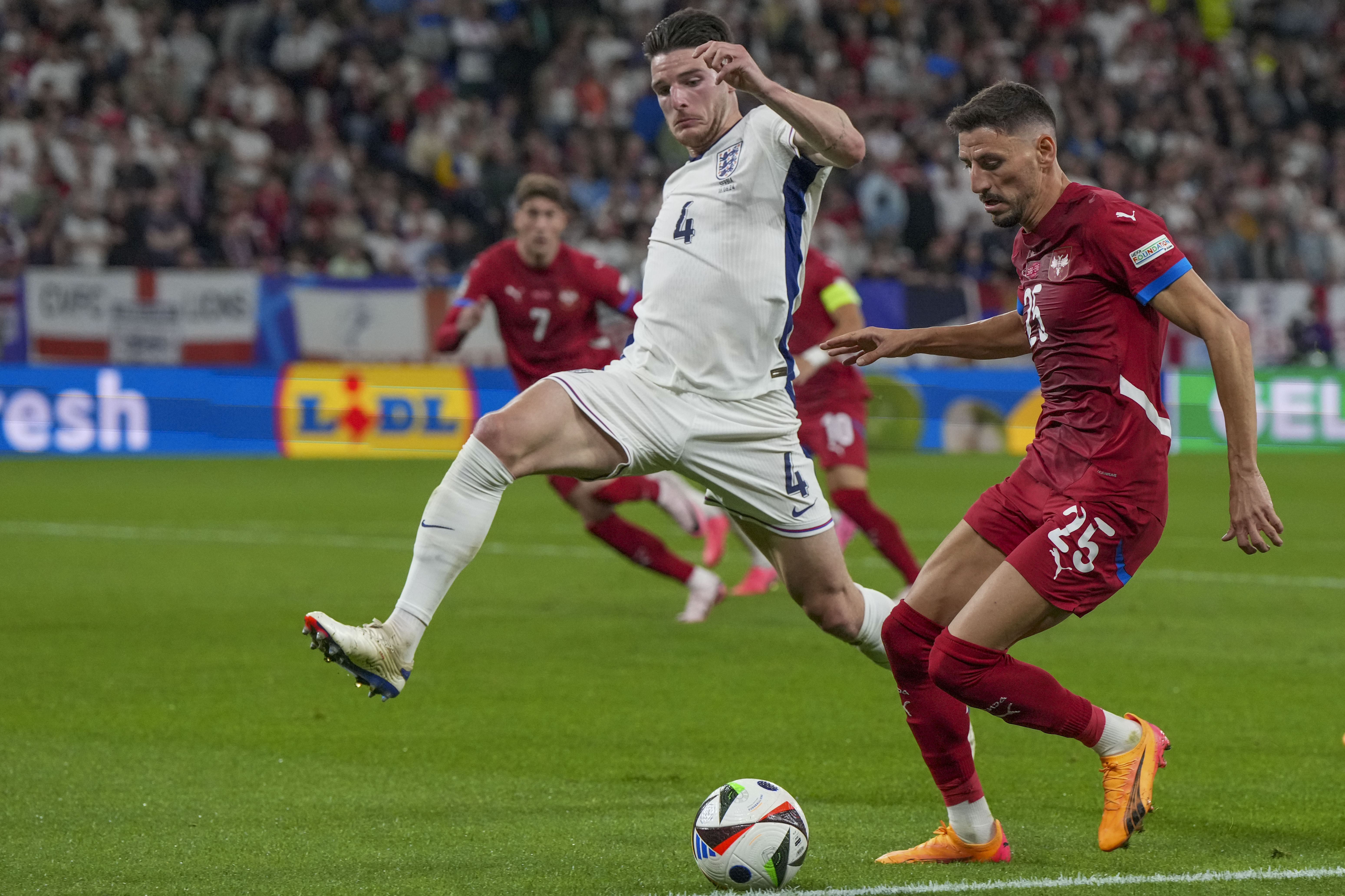 Serbia's Filip Mladenovic, right, duels for the ball with England's Declan Rice during a Group C match between Serbia and England at the Euro 2024 soccer tournament in Gelsenkirchen, Germany, Sunday, June 16, 2024. (AP Photo/Martin Meissner)
