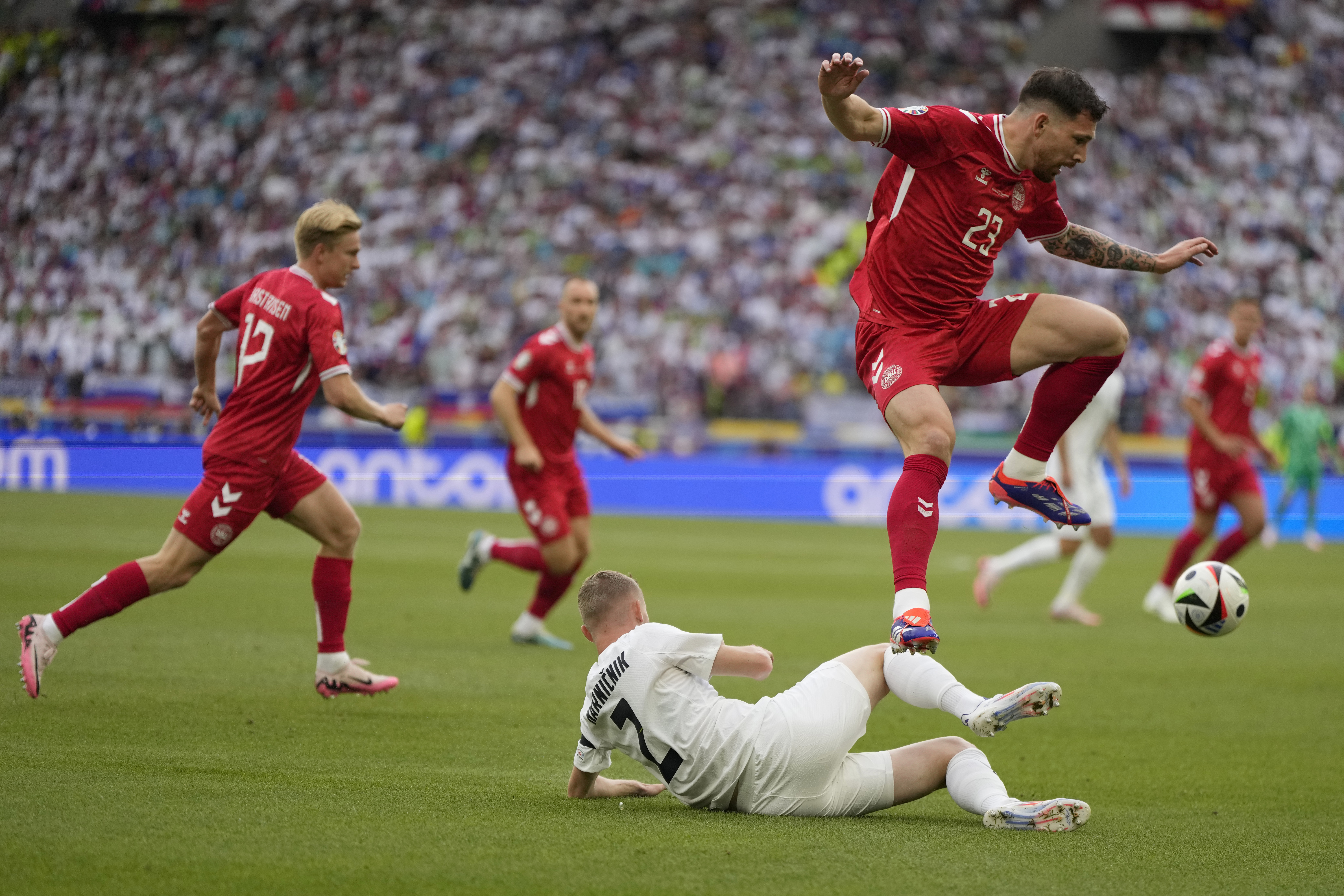 Denmark's Pierre-Emile Hojbjerg, top, avoid a tackle by Slovenia's Zan Karnicnik during a Group C match between Slovenia and Denmark at the Euro 2024 soccer tournament in Stuttgart, Germany, Sunday, June 16, 2024. (AP Photo/Matthias Schrader)