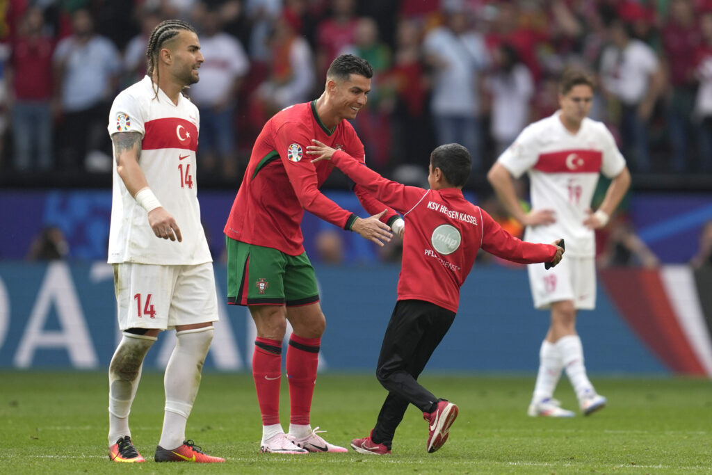 A young pitch invader goes to Portugal's Cristiano Ronaldo during a Group F match between Turkey and Portugal at the Euro 2024 soccer tournament in Dortmund, Germany, Saturday, June 22, 2024. (AP Photo/Darko Vojinovic)