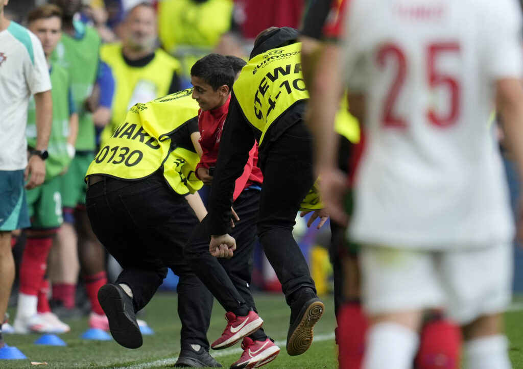 Stewards take out of the stadium a young pitch invader goes to Portugal's Cristiano Ronaldo during a Group F match between Turkey and Portugal at the Euro 2024 soccer tournament in Dortmund, Germany, Saturday, June 22, 2024. (AP Photo/Themba Hadebe)