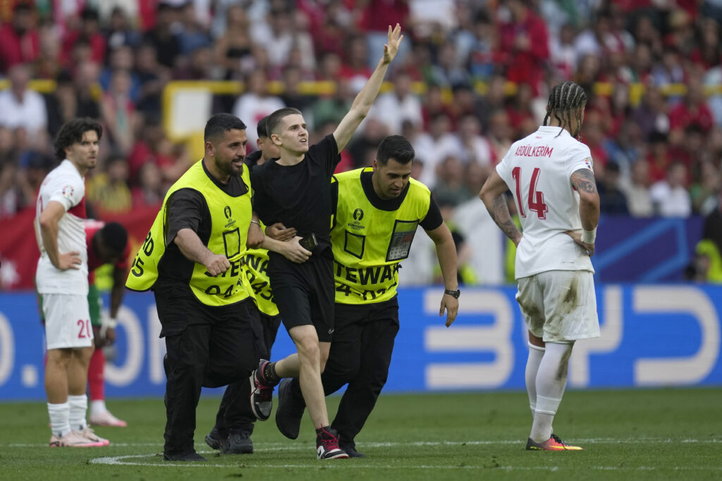 Stewards catch a pitch invader that ran to Portugal's Cristiano Ronaldo during a Group F match between Turkey and Portugal at the Euro 2024 soccer tournament in Dortmund, Germany, Saturday, June 22, 2024. (AP Photo/Darko Vojinovic)