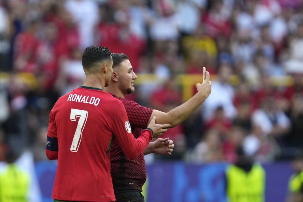 A pitch invader takes a selfie with Portugal's Cristiano Ronaldo during a Group F match between Turkey and Portugal at the Euro 2024 soccer tournament in Dortmund, Germany, Saturday, June 22, 2024. (AP Photo/Darko Vojinovic)