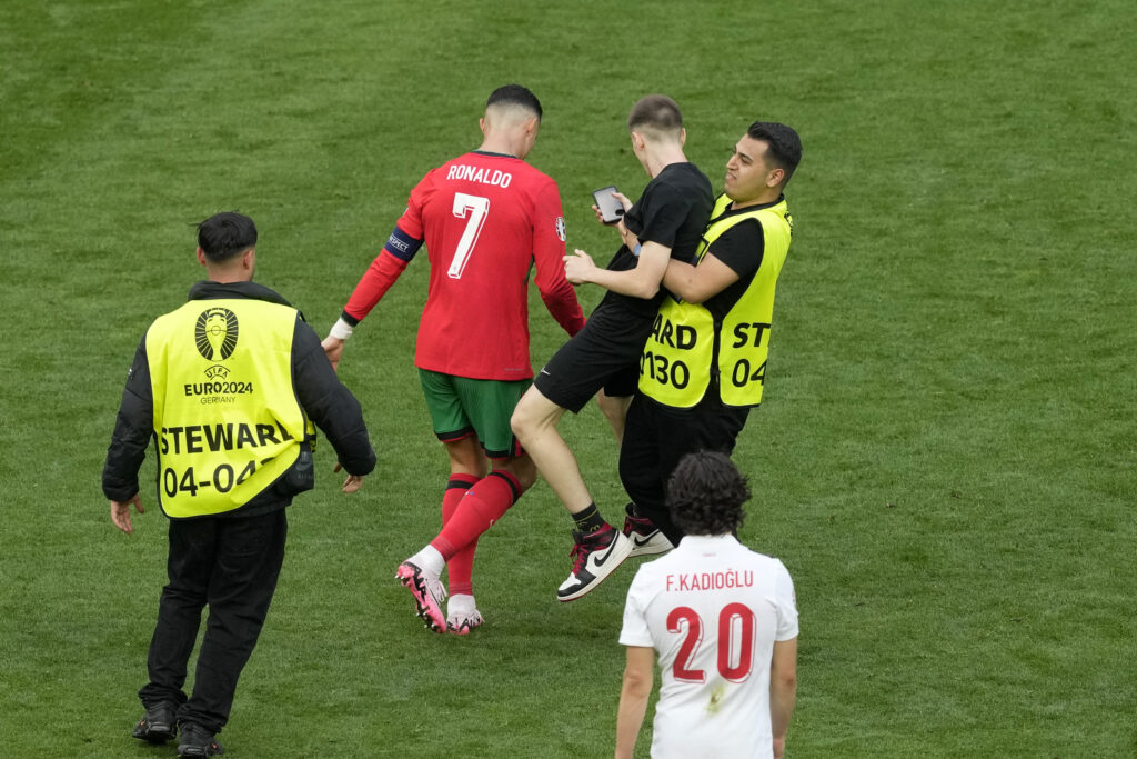Stewards catch a pitch invader that ran to Portugal's Cristiano Ronaldo during a Group F match between Turkey and Portugal at the Euro 2024 soccer tournament in Dortmund, Germany, Saturday, June 22, 2024. (AP Photo/Michael Probst)
