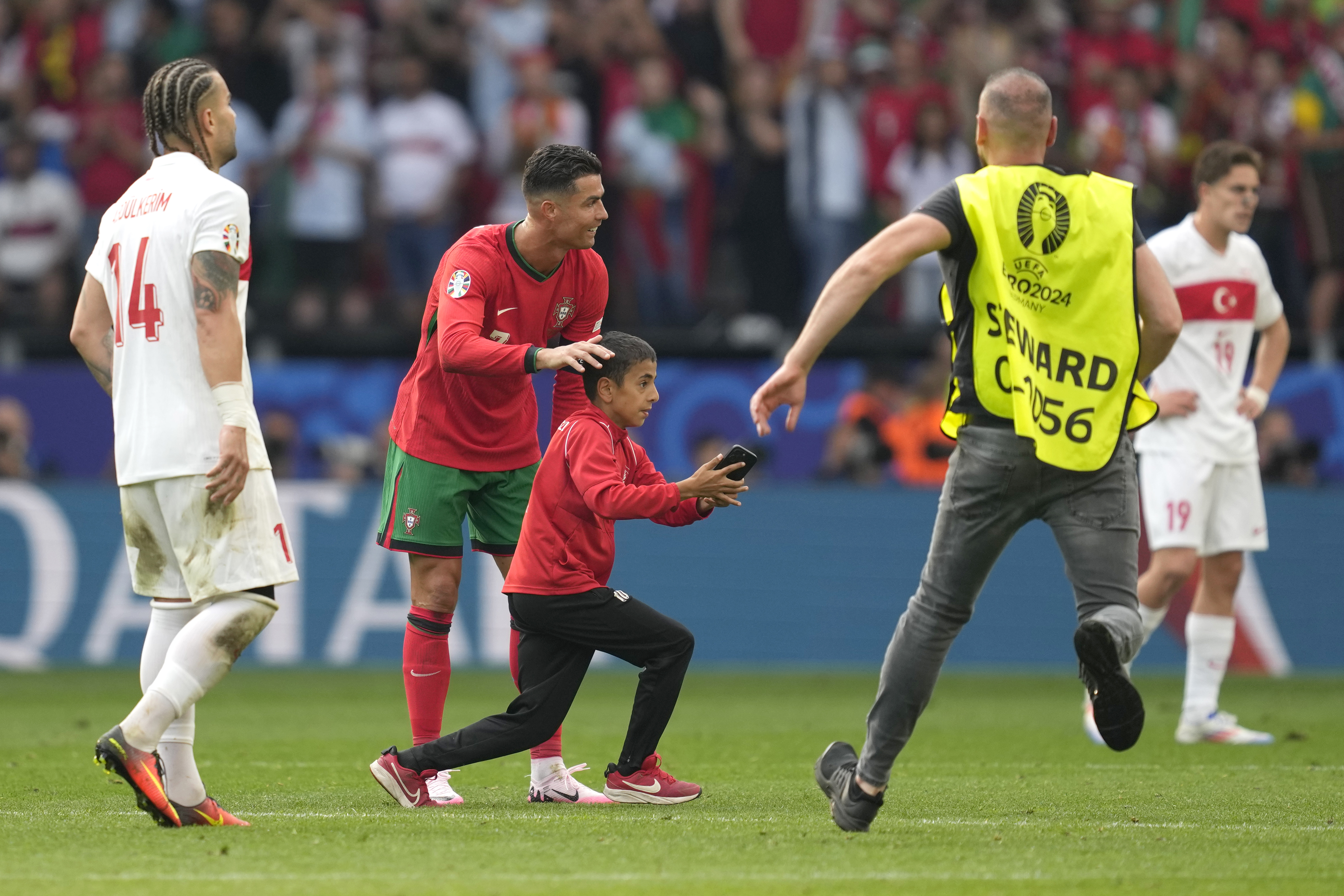 Steward tries to catch a young pitch invader who ran to Portugal's Cristiano Ronaldo during a Group F match between Turkey and Portugal at the Euro 2024 soccer tournament in Dortmund, Germany, Saturday, June 22, 2024. (AP Photo/Darko Vojinovic)