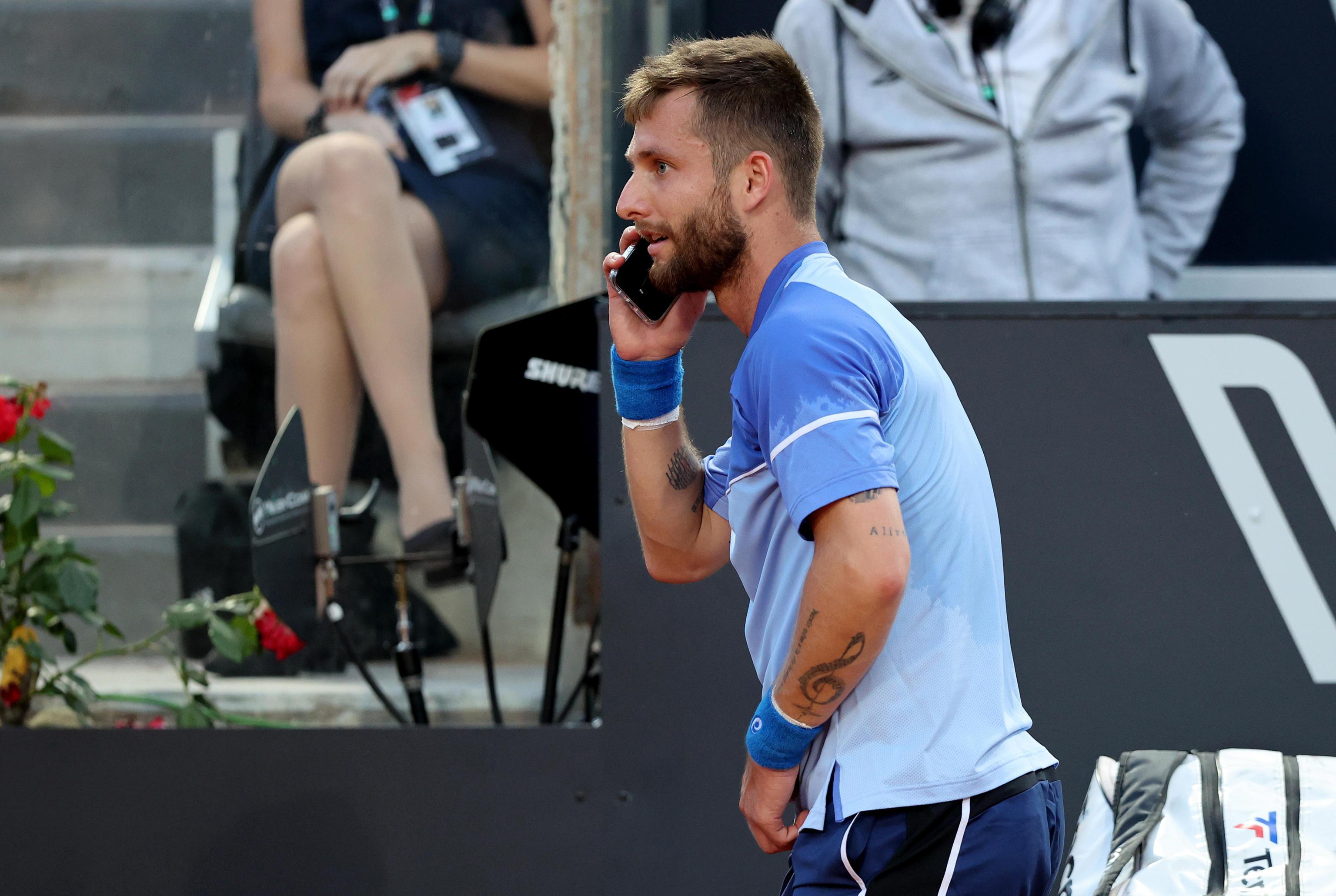 epa11331928 Corentin Moutet of France jokes with a cell phone as he plays against Novak Djokovic of Serbia (not pictured) during their men's singles match at the Italian Open tennis tournament in Rome, Italy, 10 May 2024.  EPA-EFE/ETTORE FERRARI