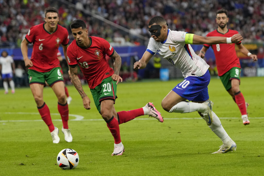 Portugal's Joao Cancelo challenges for the ball with Kylian Mbappe of France during a quarter final match between Portugal and France at the Euro 2024 soccer tournament in Hamburg, Germany, Friday, July 5, 2024. (AP Photo/Andreea Alexandru)